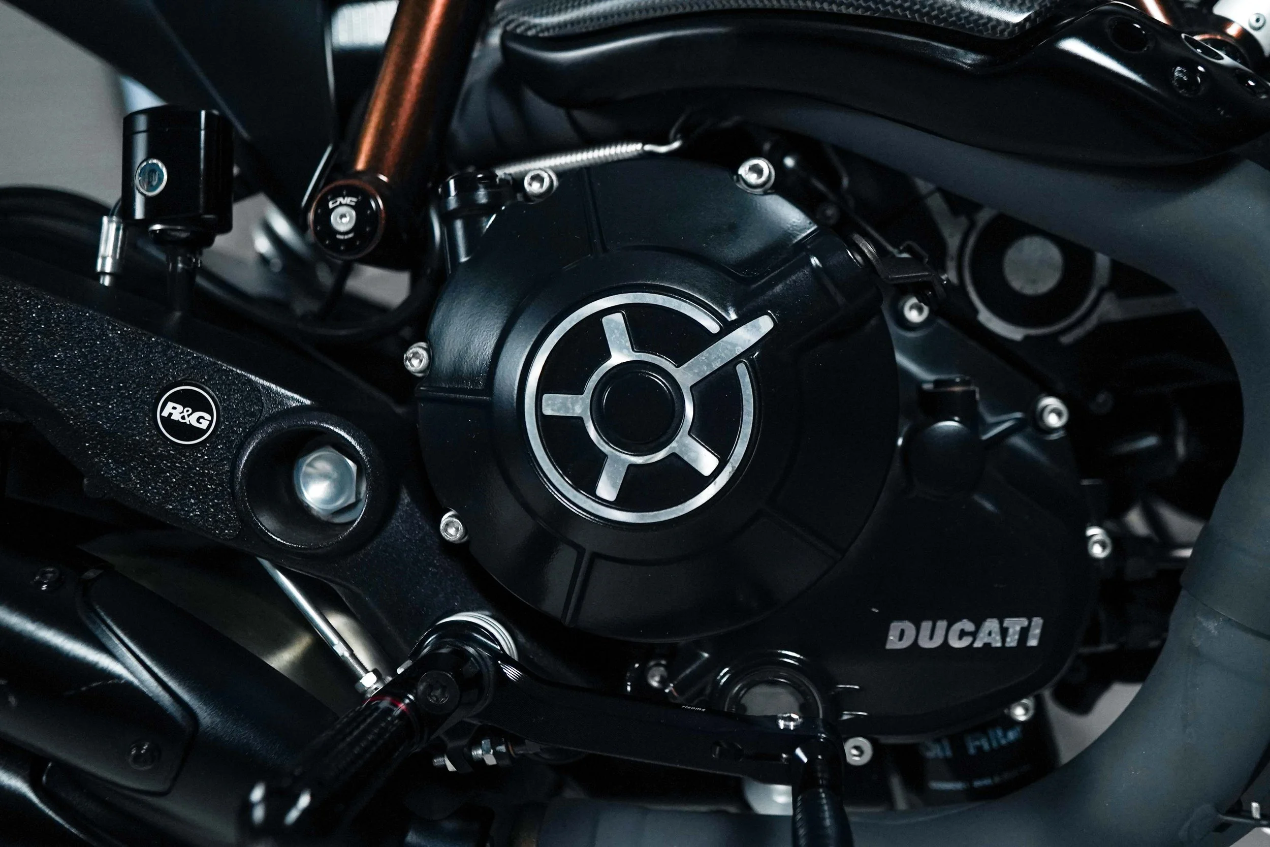 Close-up of a Ducati motorcycle engine with visible parts, bolts, and a black cover with the Ducati logo.