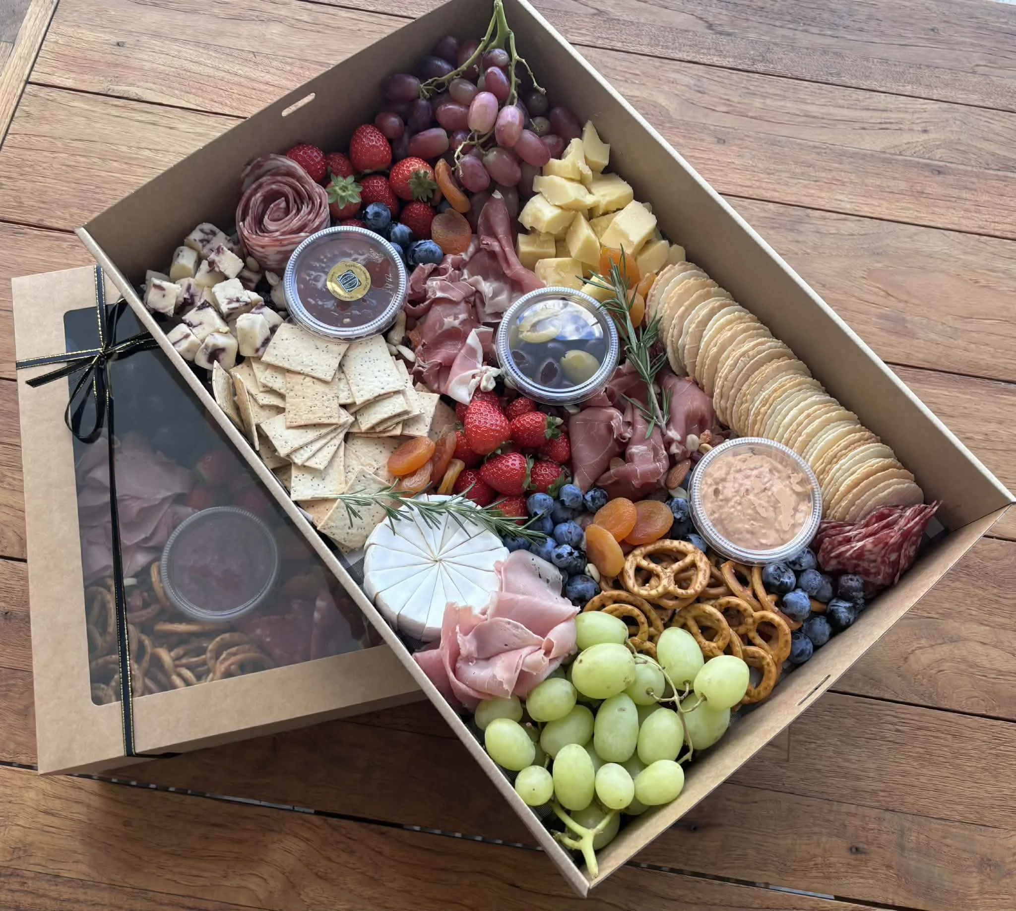 Cheese, grapes, strawberries, blueberries, crackers, and meats arranged on a rectangular platter.