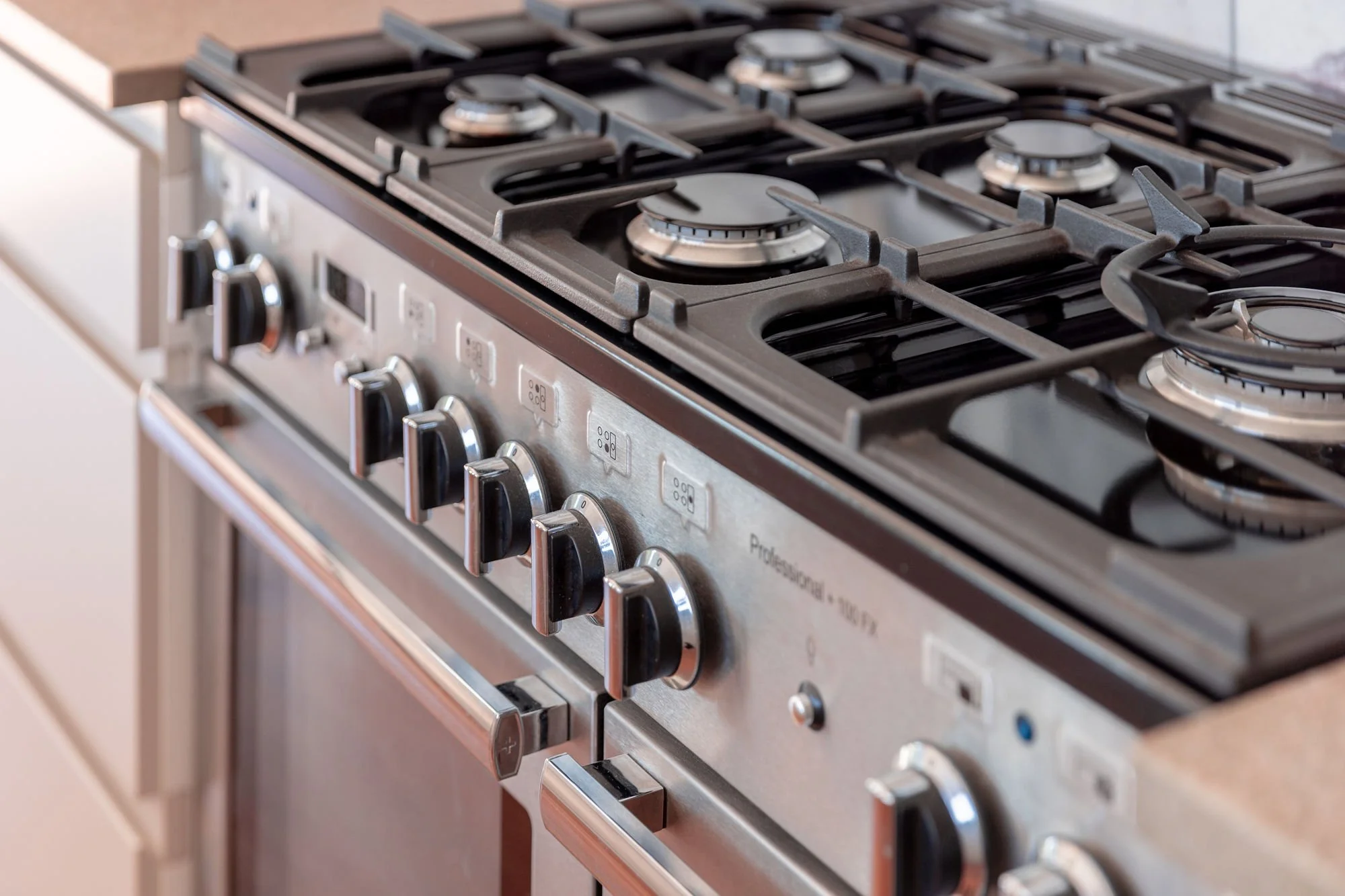 A stainless steel gas stove with six burners and control knobs below.