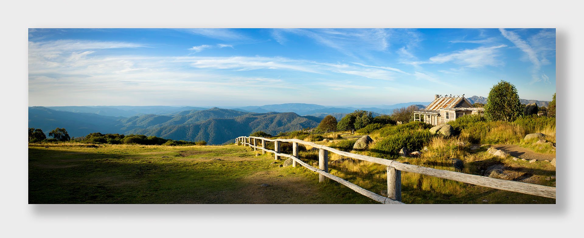 Panorama of Craig’s Hut near Mount Stirling in the Victorian High Country, with a rustic timber fence leading past the hut and forested ranges stretching to the horizon.