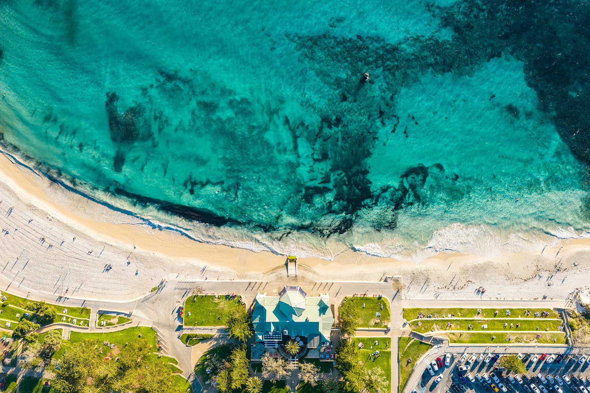 Drone view looking straight down on the Indiana Tea House at Cottesloe Beach, Perth, Western Australia, with turquoise water, reef patches, white sand and terraced grassy lawns.
