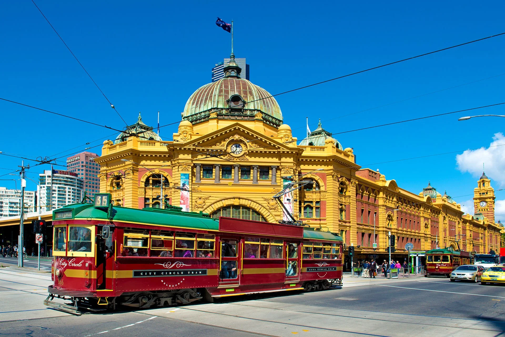 Red tram passes in front of Flinders Street Station, Melbourne