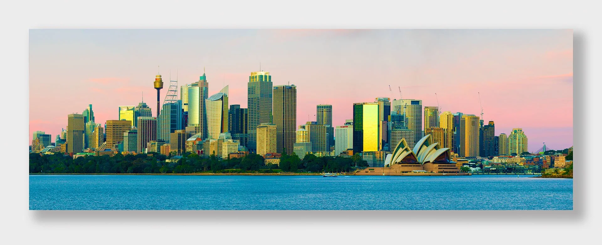 Panorama of the Sydney city skyline and Sydney Opera House across the harbour, New South Wales, with Sydney Tower and the Royal Botanic Garden glowing under a pink dusk sky.