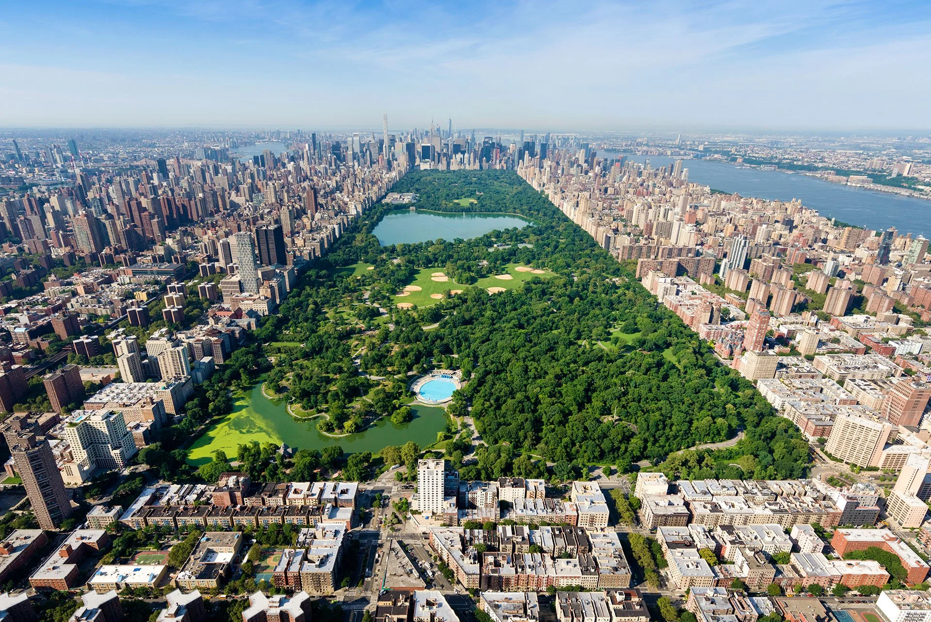 Aerial view looking south over Central Park, New York City, from Harlem Meer past the reservoir to the Midtown Manhattan skyline, with the Hudson River on the right.