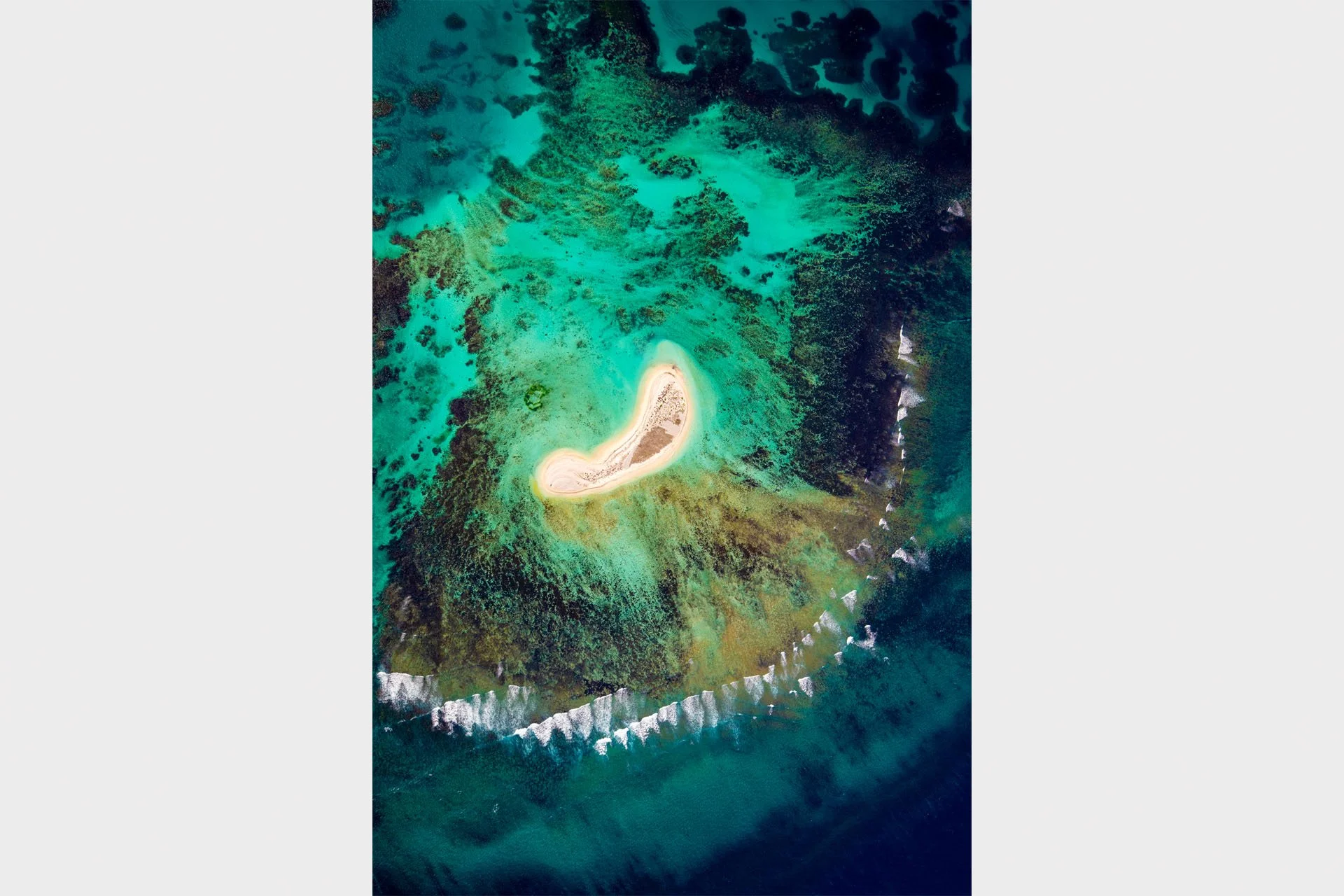 Bird’s eye view looking straight down on Sandy Island, a small white sand cay ringed by coral reef and breaking surf in the Houtman Abrolhos Islands, Western Australia.
