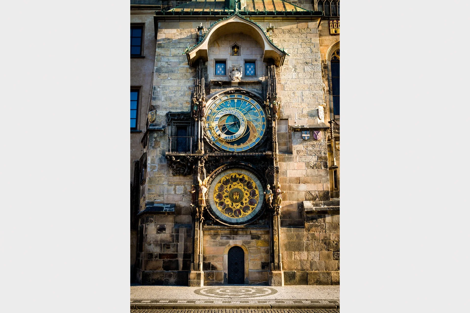 The medieval Prague Astronomical Clock on the Old Town Hall, Prague, Czech Republic, with its blue astronomical dial and gold calendar dial lit by warm sunlight.
