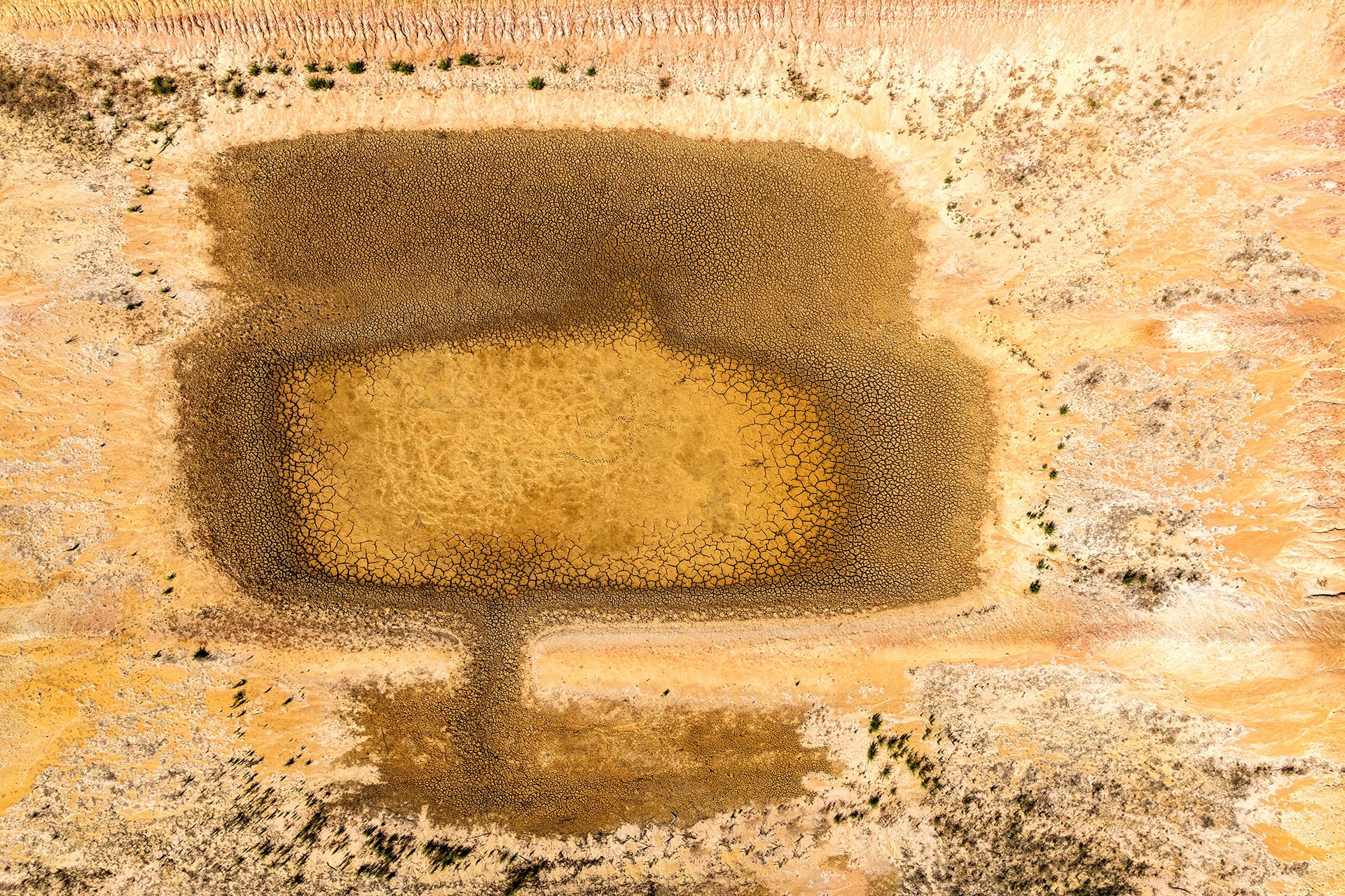 Aerial of a dry dam with cracked mud and abstract patterns