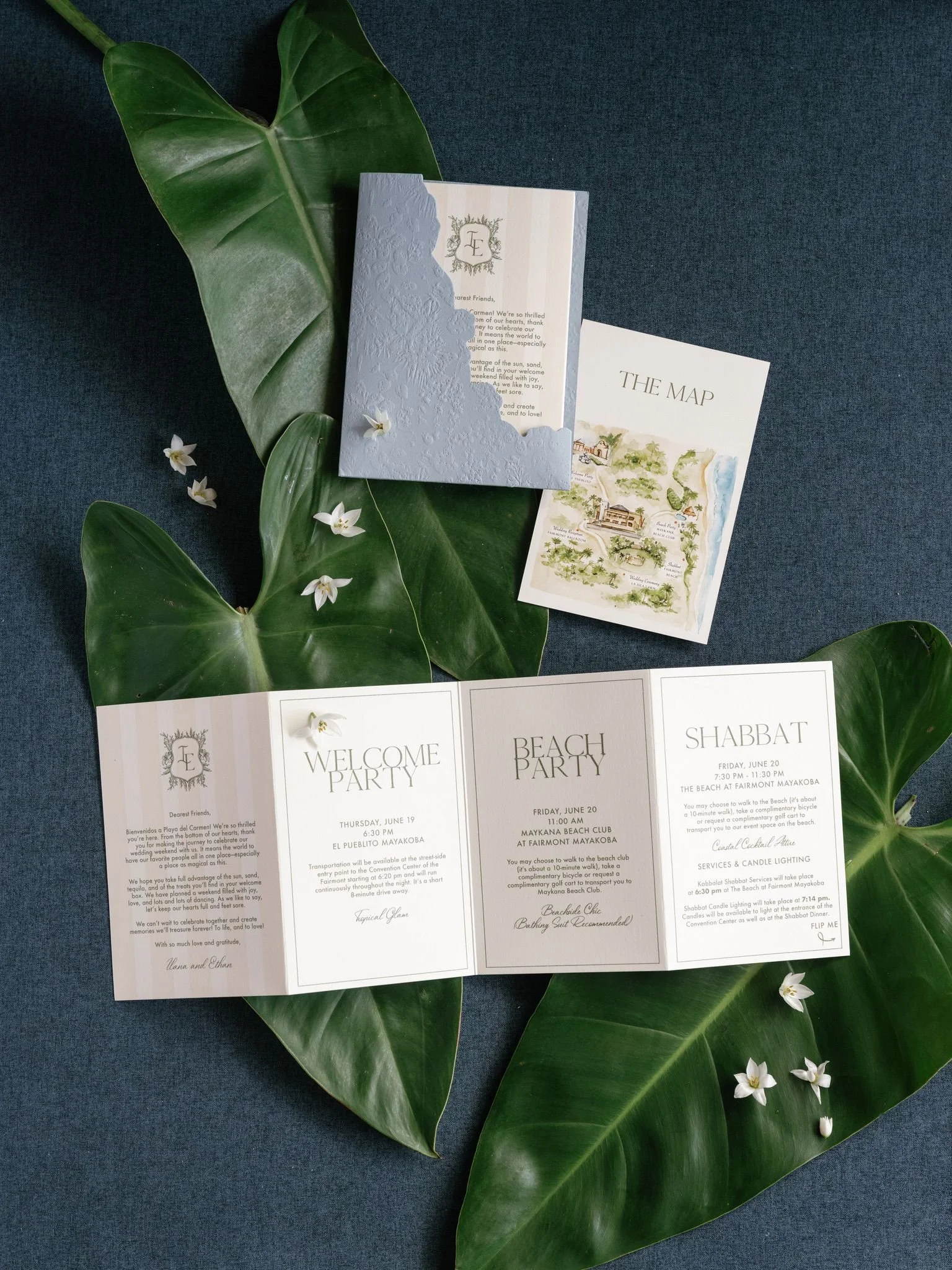 A wedding event program printed on white paper, with garden illustrations and schedule details, surrounded by large green leaves and small white flowers on a blue background.