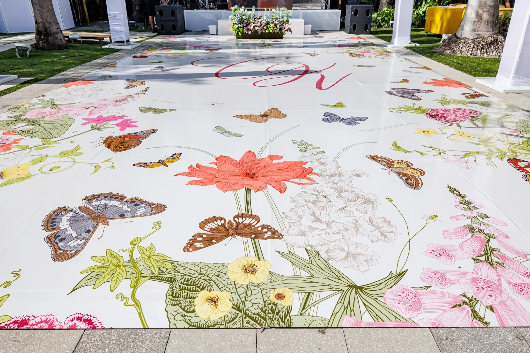 A decorated floor with a floral and butterfly design, possibly for a wedding or event, featuring various flowers and butterflies in vibrant colors.
