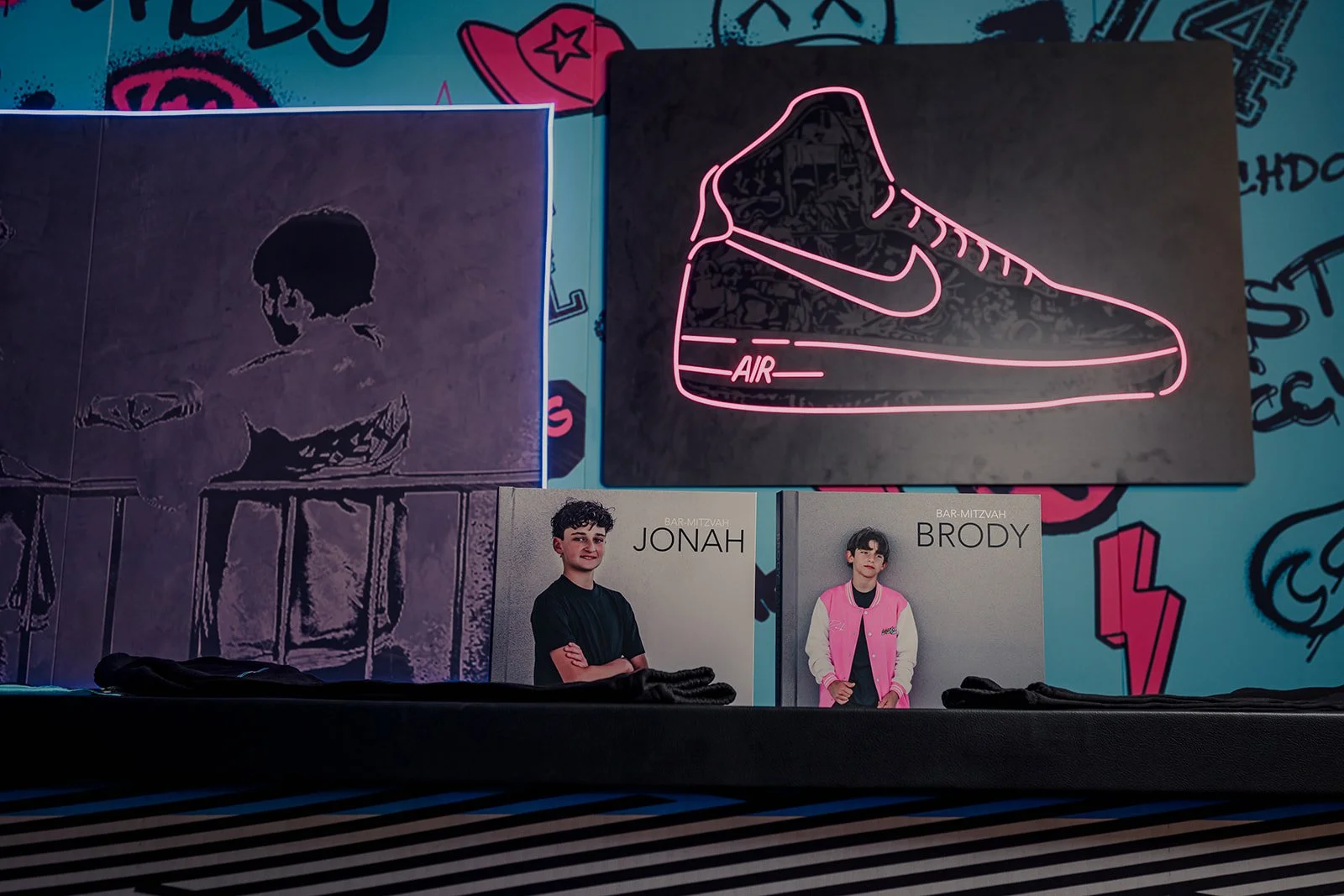 Neon sign of a pink Nike Air sneaker and a younger man photo display below.