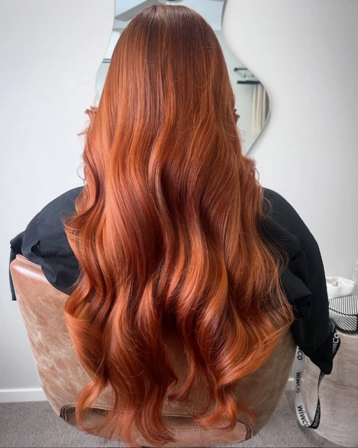 Back of a person's head with long, wavy, reddish-orange hair.