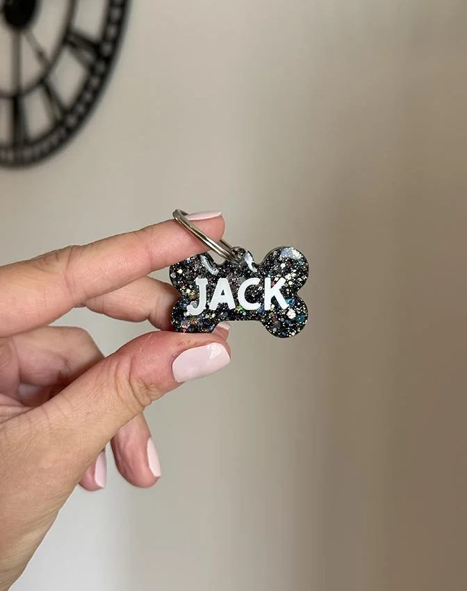 Un porta chiave con un pendente a forma di ossicino, con brillantini neri e scritta personalizzata color bianco