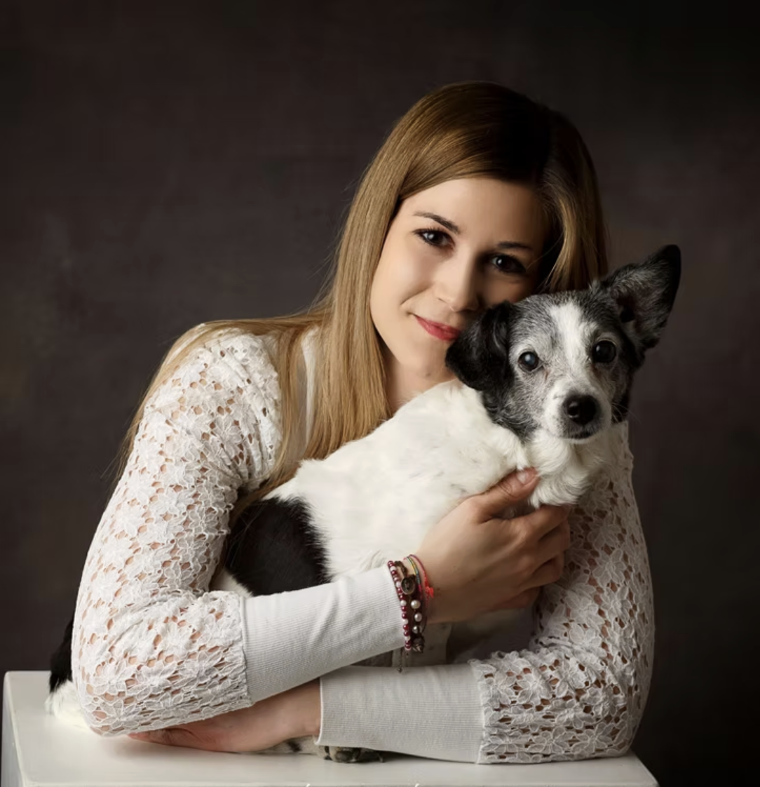Ragazza con capelli lunghi che abbraccia un cane con orecchie grandi e pelo bianco e nero.