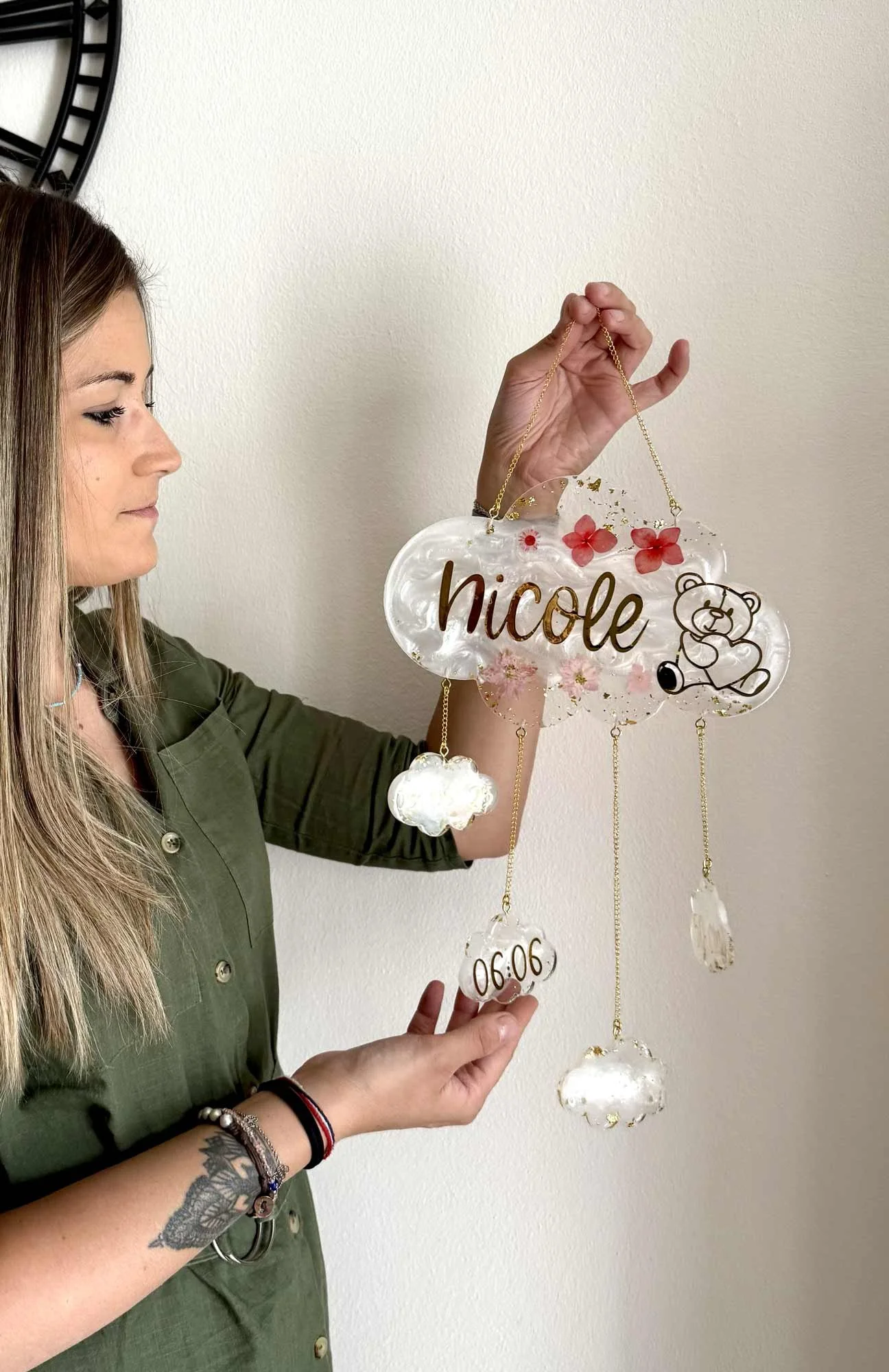 Decorazioni di resina con il nome Nicole, simbolo di un orsetto e un fiocco di neve, appese a una parete bianca.