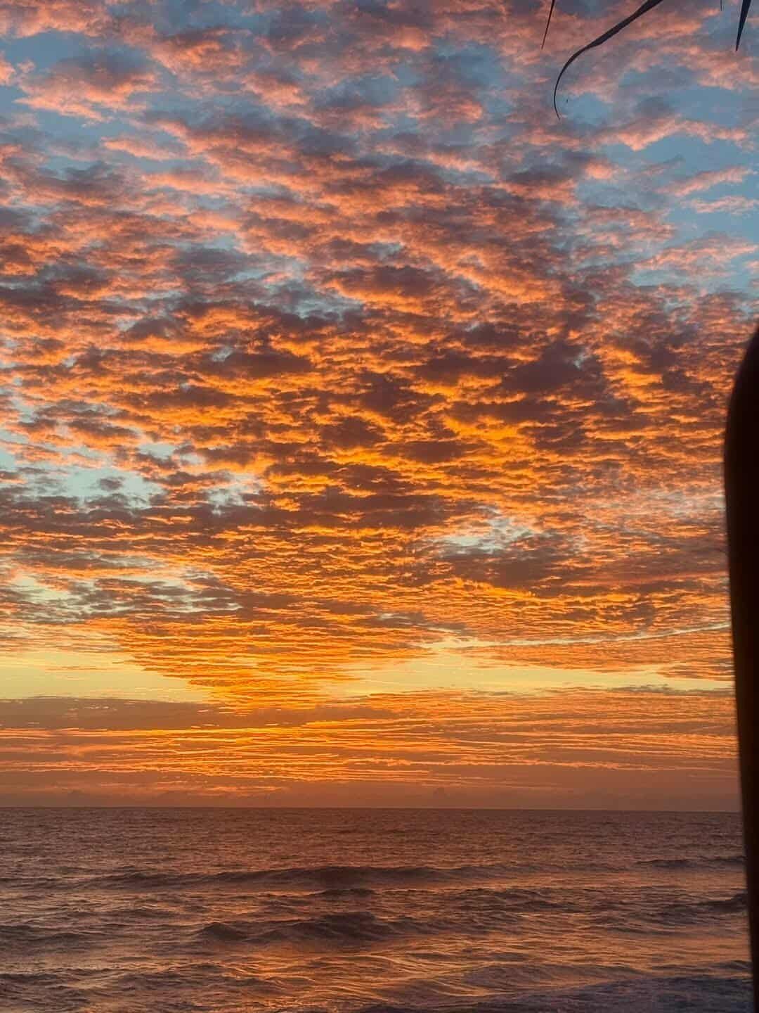 Sunset over the ocean with orange and pink clouds in the sky.
