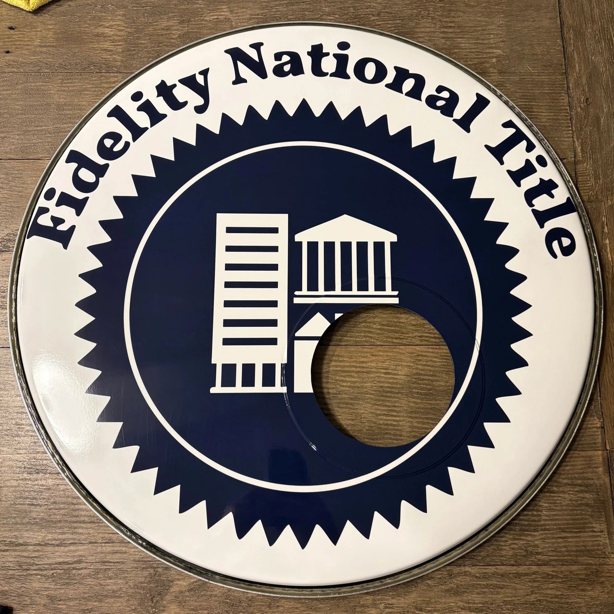 Close-up of a circular sign wrapped with 3m IJ180 vinyl, laminated in 3m 8518, displaying the text 'Fidelity National Title" and the logo including columns and a building.