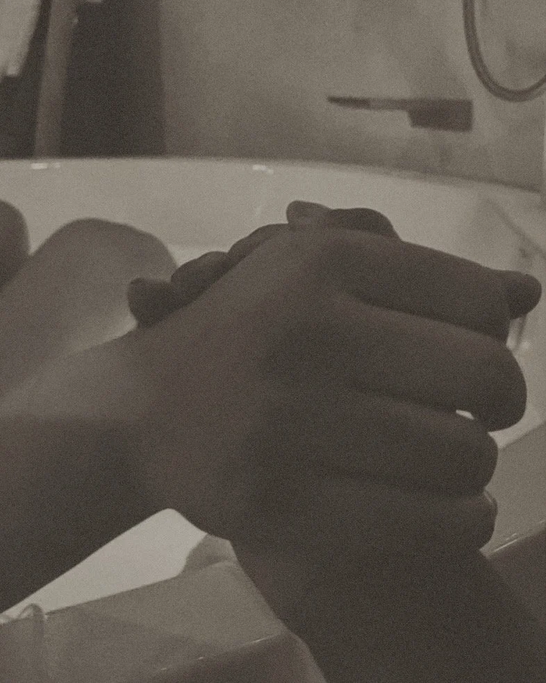 A person holding their hands together in front of a washing machine or dryer.