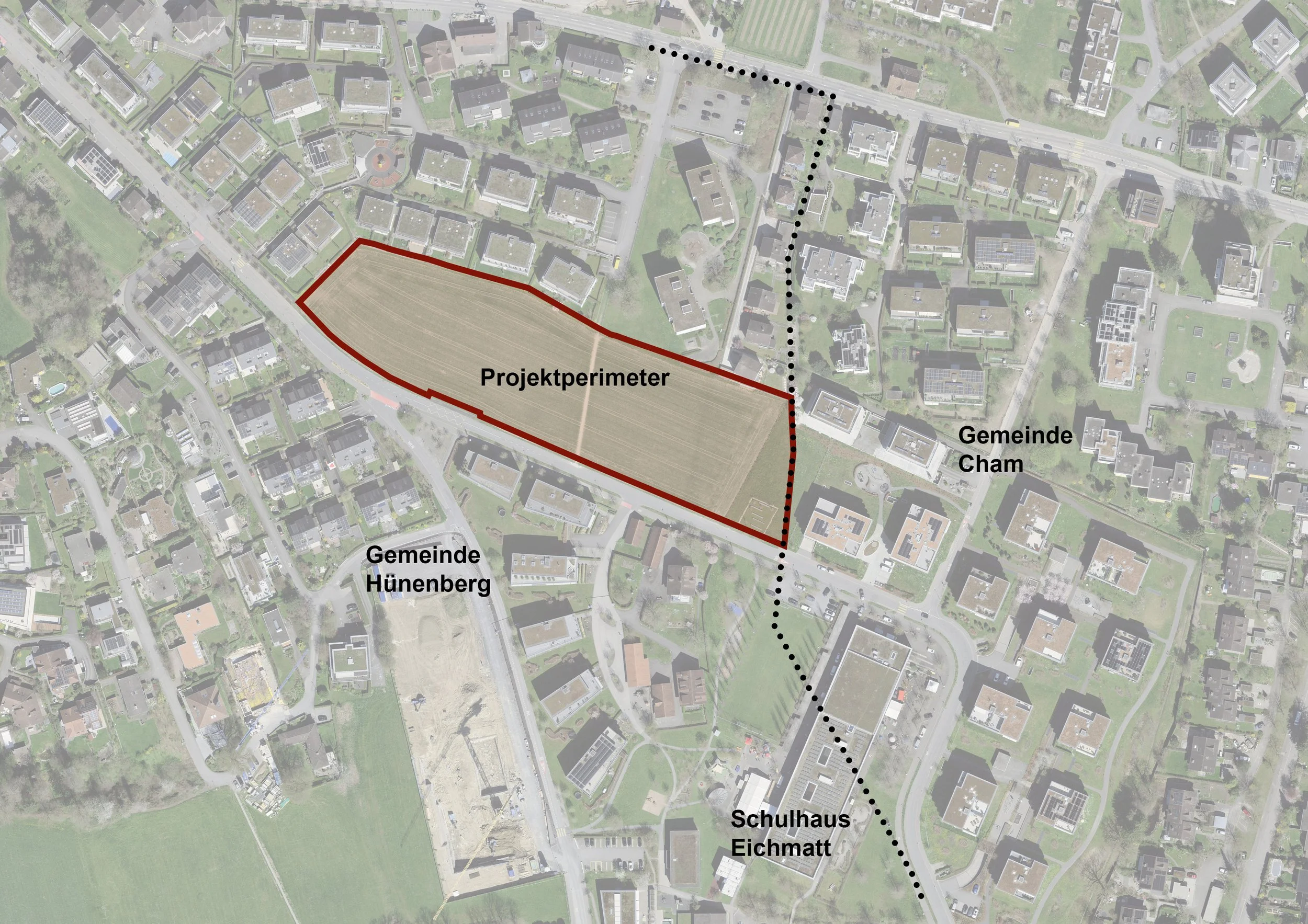 Luftaufnahme eines Stadtgebietes mit markiertem Gebiet, das durch eine rote Linie umgrenzt ist, mit der Bezeichnung 'Projektperimeter'. Das Gebiet befindet sich zwischen der Gemeinde Hünnenberg im Südwesten, Gemeinde Cham im Nordosten, und ist entlang einer Reihe von mehreren Gebäuden, Straßen und grünen Freiflächen. Es gibt Beschriftungen für Schulen, die innerhalb des Projektperimeters liegen, darunter 'Schulhaus Eichamt'.