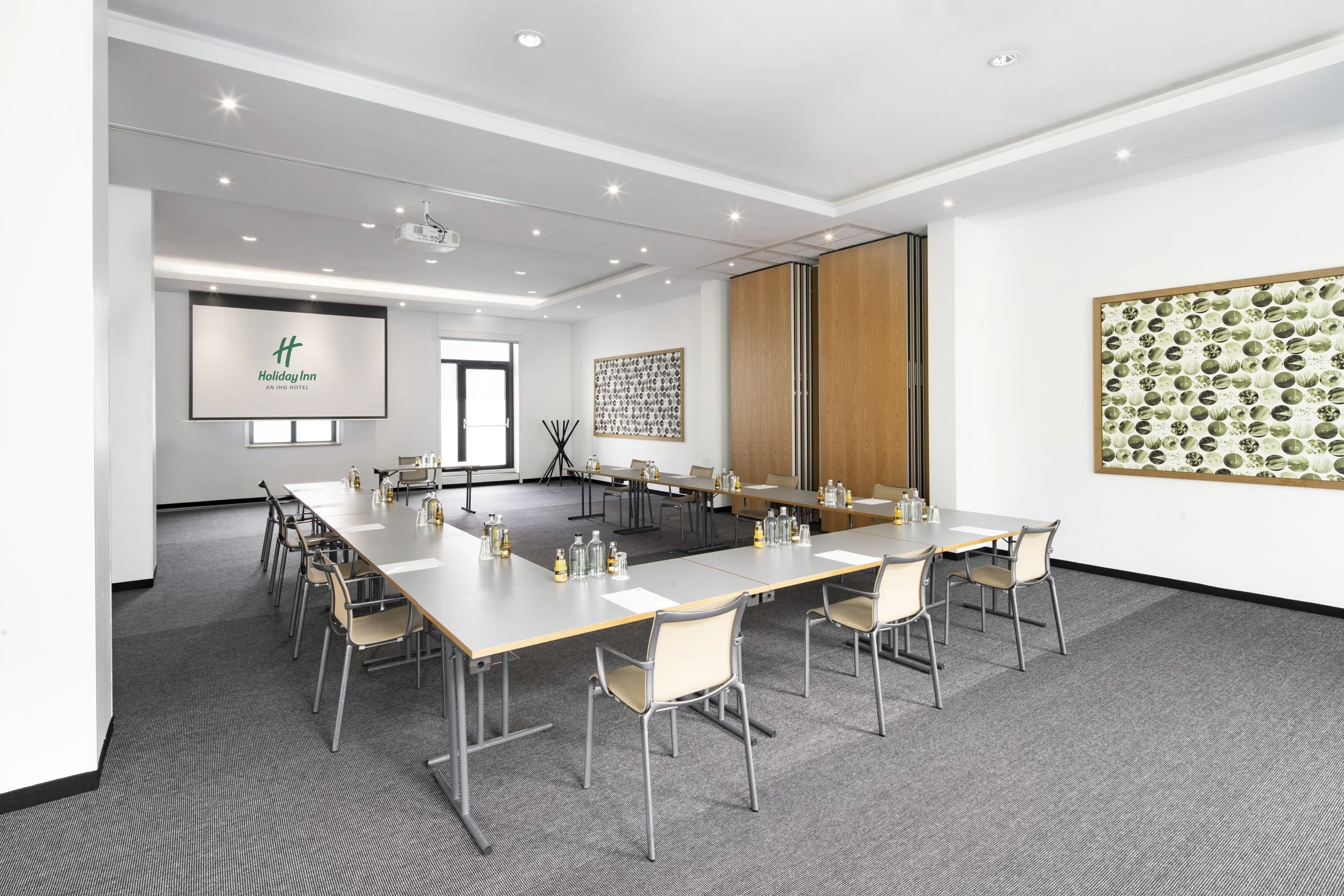 Conference room with tables, chairs, water bottles, and a projector, in a hotel meeting space