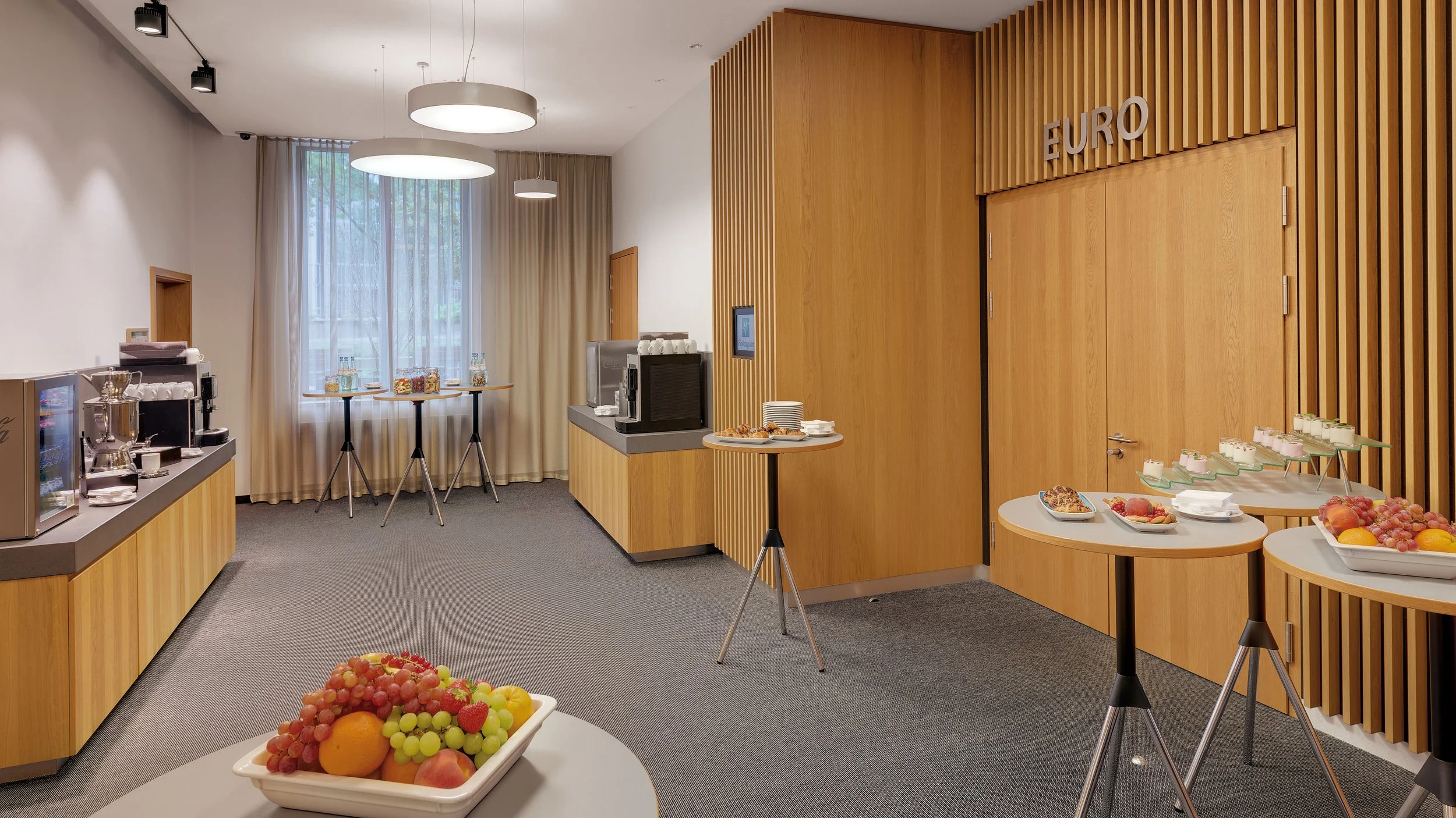 A breakfast buffet area with fruit, pastries, and beverages, labeled "EURO."