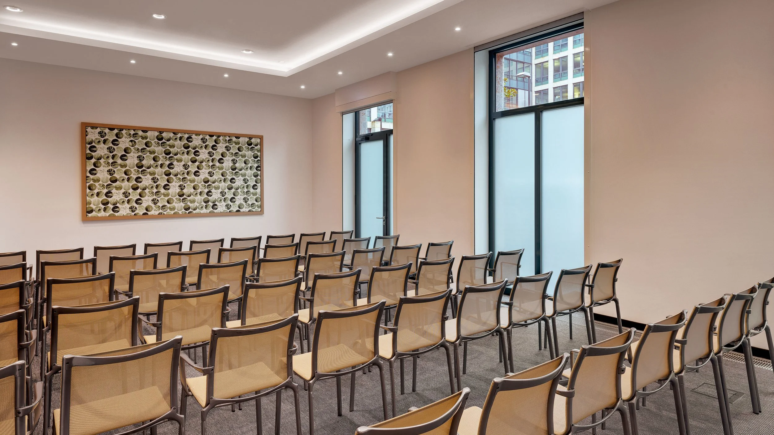Empty conference room with rows of chairs, large windows, and modern decor.