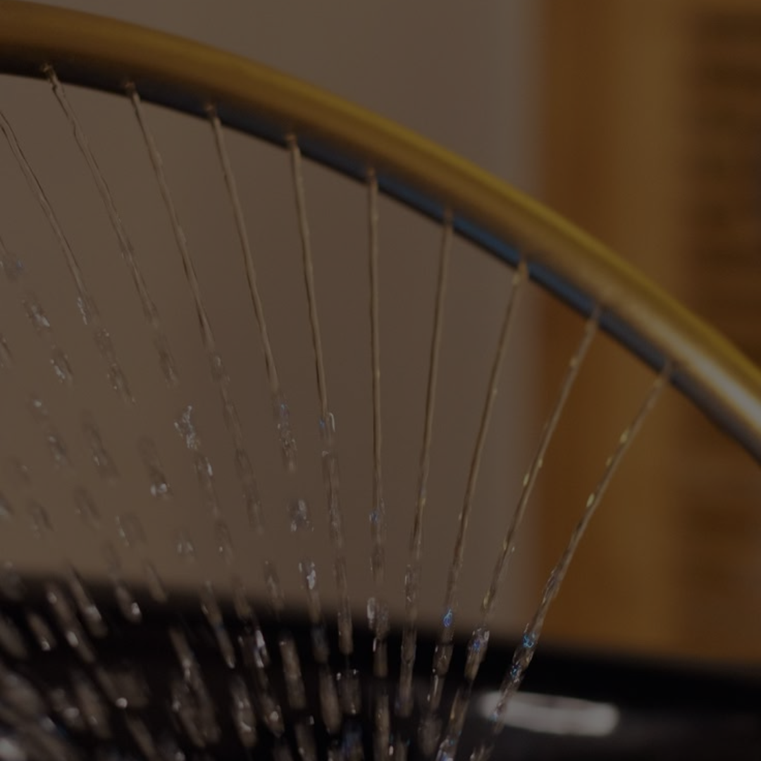 Close-up of a shower head with water spraying through its nozzles.