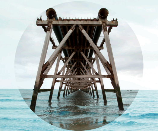Underwater view of a wooden pier extending into the ocean with waves below.