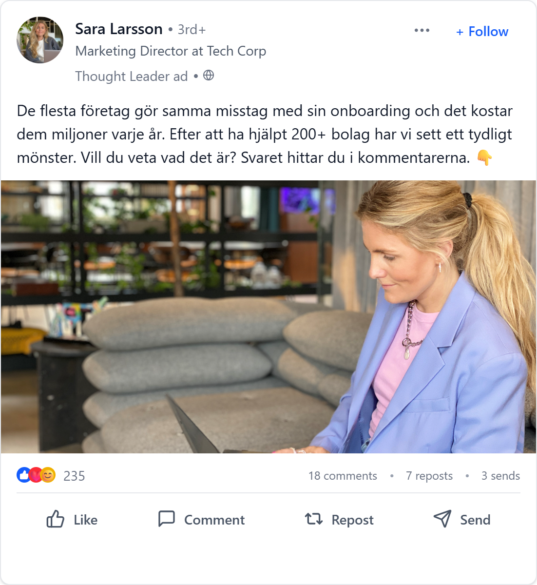En ung kvinna med blond hår i hästsvans, iklädd ljusblå kavaj och rosa topp, sitter i ett mysigt inomhusmiljö med en laptop.