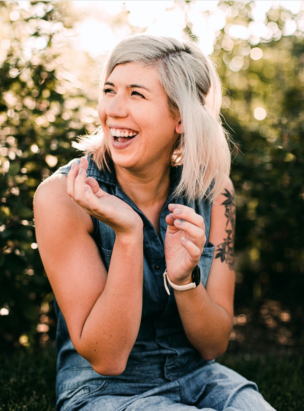 woman sitting, smiling with her hands raised