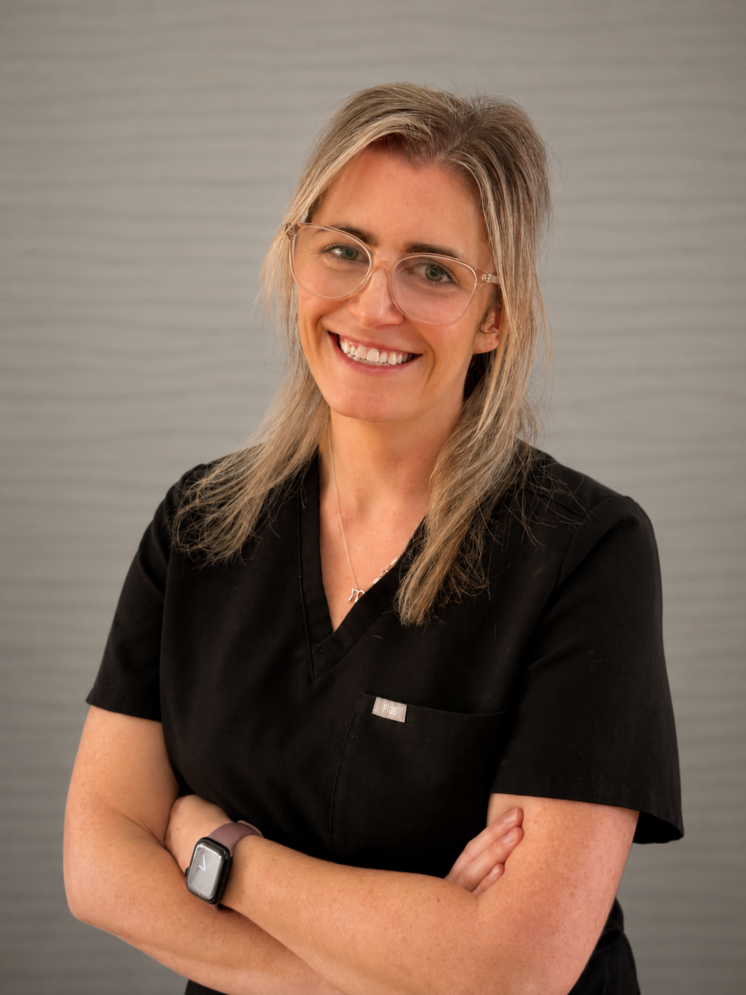 Rebecca is smiling with her arms crossed, posed towards the camera.