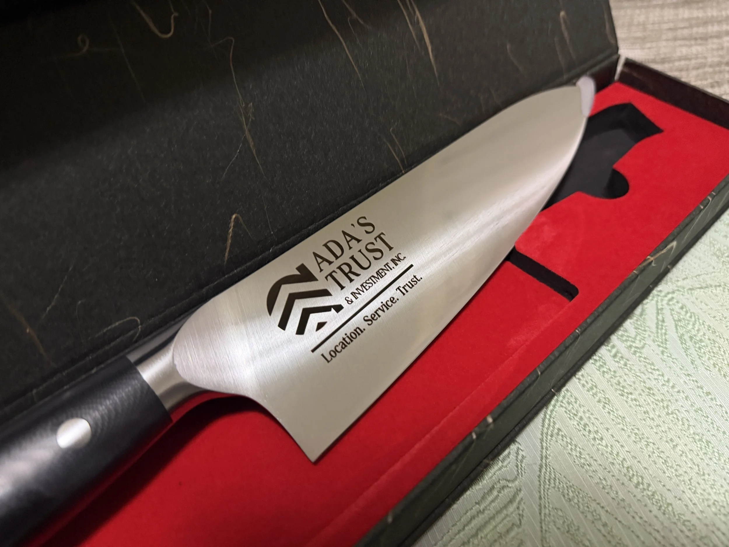 Close-up photo of a metal tube with text on it, surrounded by a black and red box, placed on a patterned green surface.