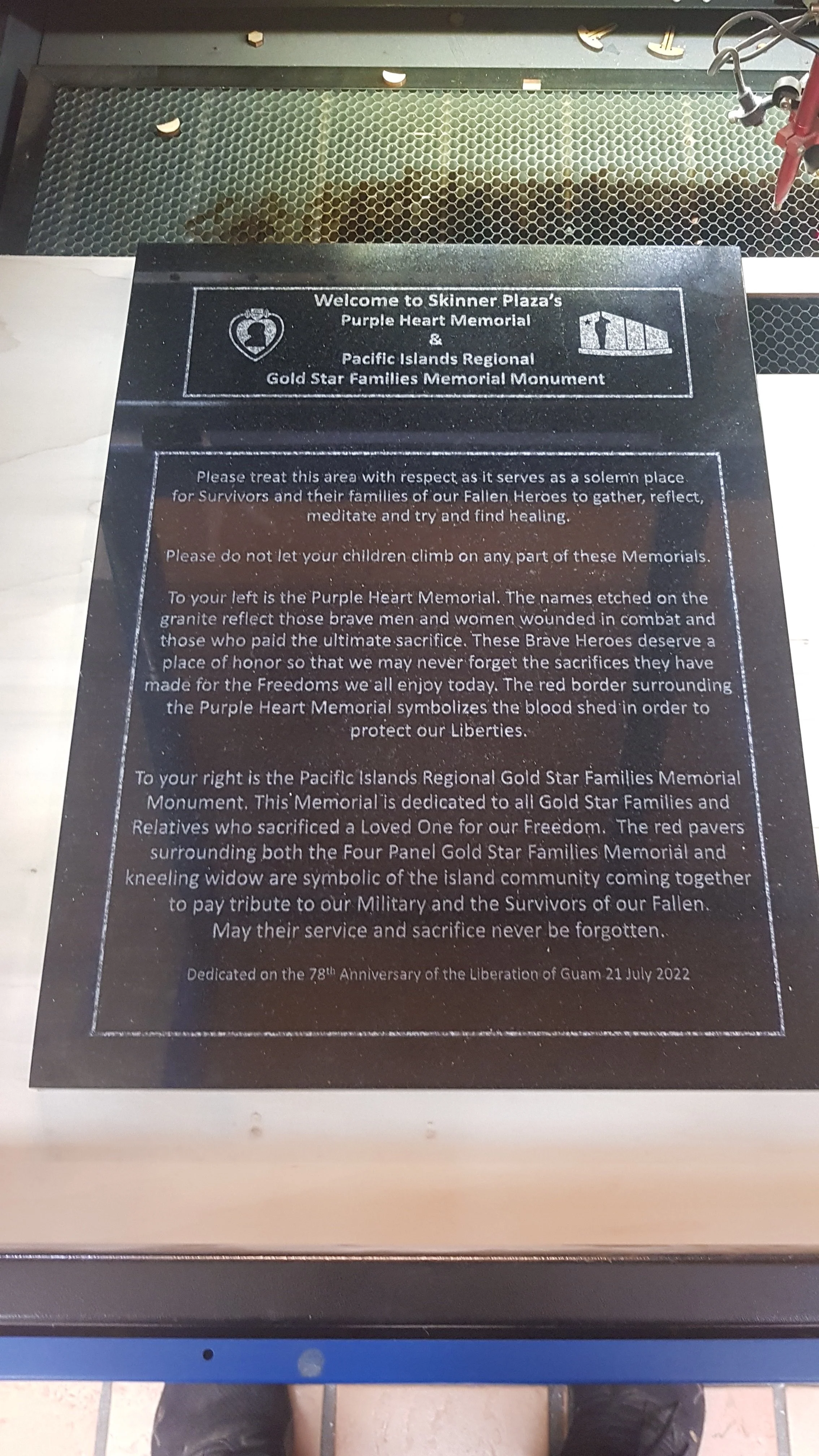 Sign at a memorial with text explaining the Purple Heart Memorial and the Gold Star Families Memorial Monument, including instructions to treat the area with respect and details about the symbols and purpose of the memorials.