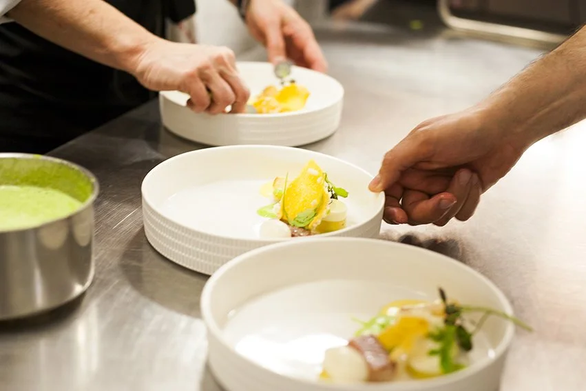 Zorgvuldige afwerking van gerechten voor een exclusieve private dining beleving.