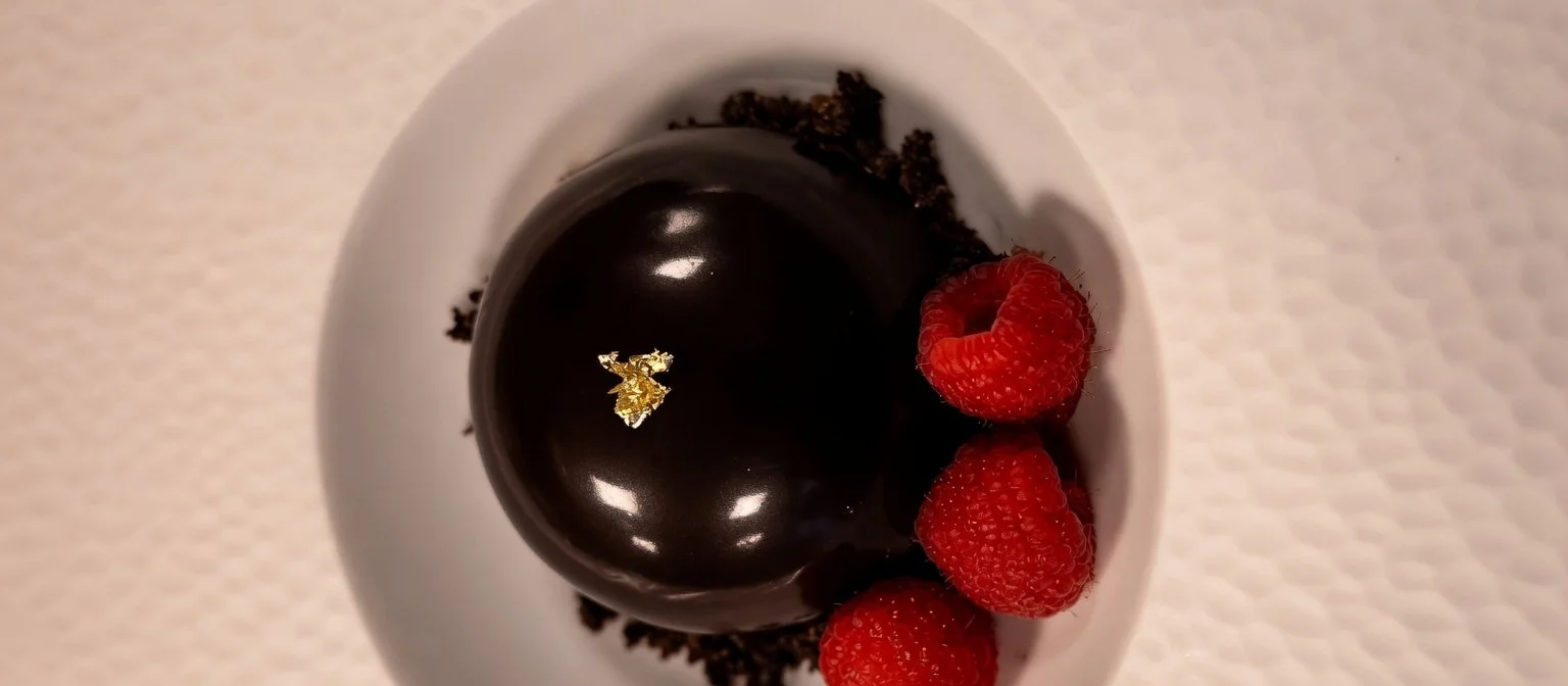 Dôme met chocolade en framboos, afgewerkt met glanzend chocoladeglazuur door Ann Steyaert Atelier.