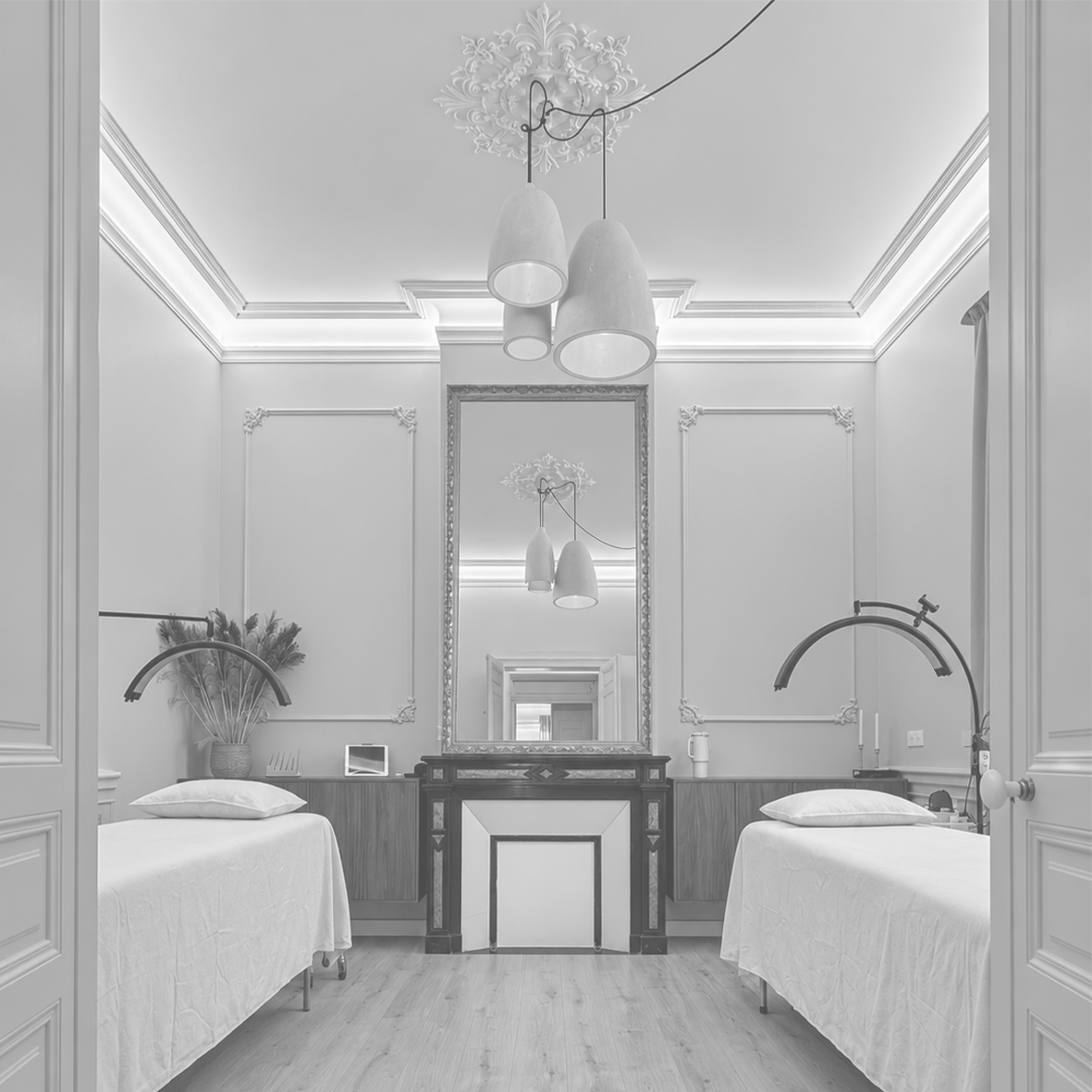Aménagement intérieur d’un institut de beauté à Mauguio : deux postes de soins esthétiques, moulures murales, miroir central et luminaires suspendus.