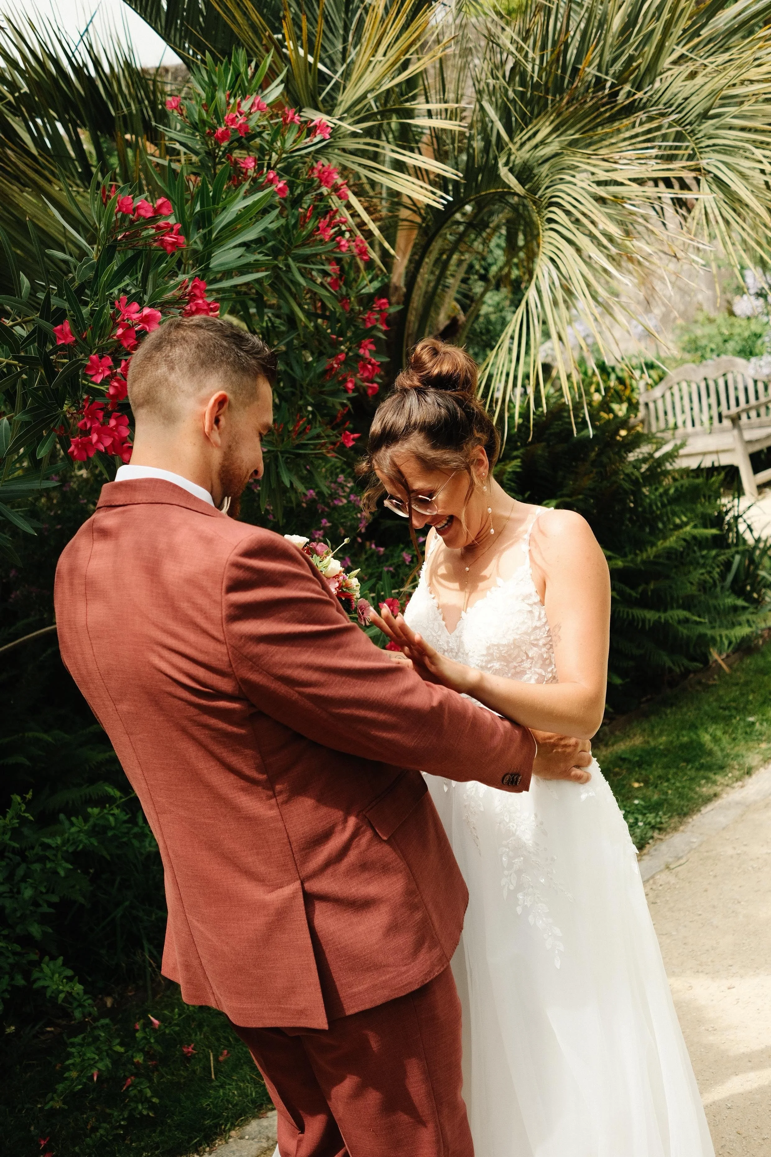 Un couple lors d'un mariage, en train de s'embrasser avec un décor de végétation luxuriante autour d'eux.