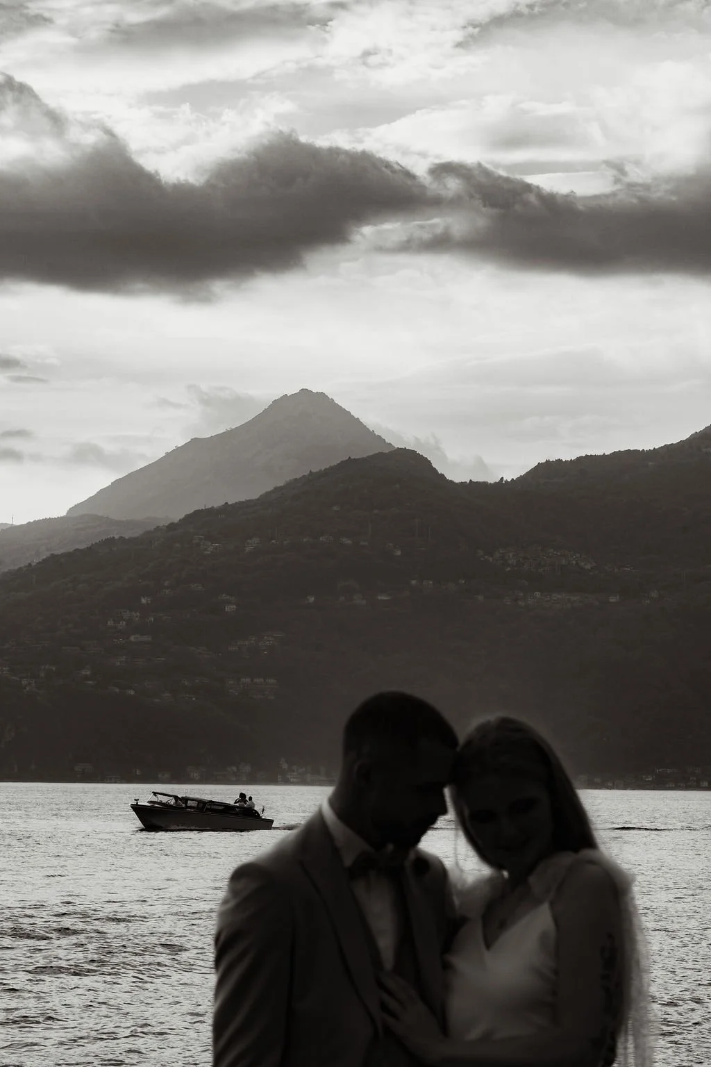 Couple standing in front of Lake Como with mountains in the background, Varenna, Italy.