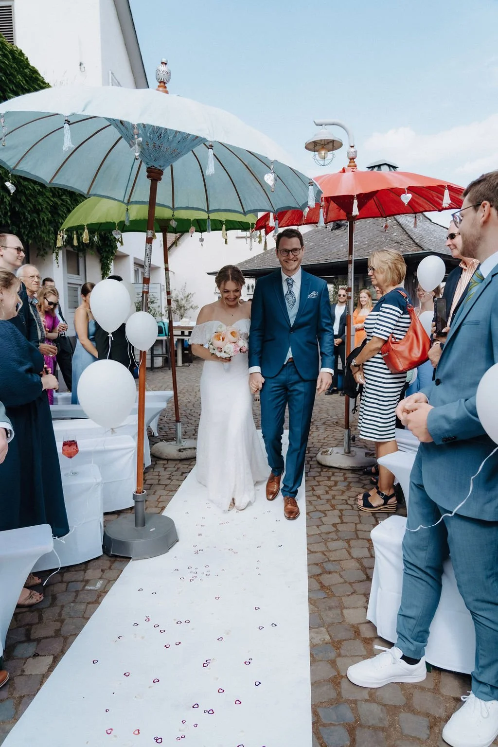 Couple is walking to their wedding ceremony, surrounded by family and friends in Hochheim, Germany.