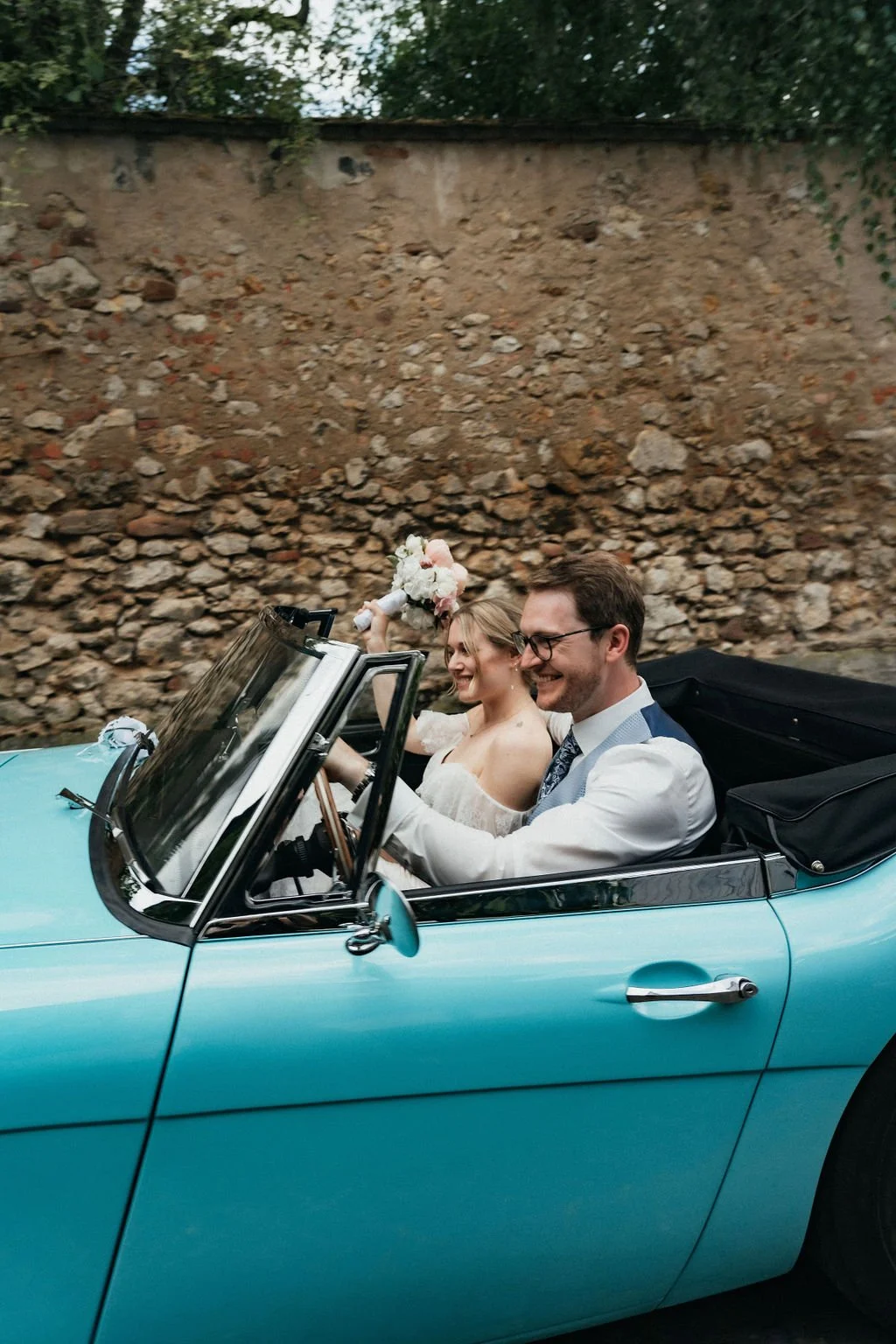 Groom and bride driving by in a classic car captured by cinematic wedding photographer Jessica Di Salvo.