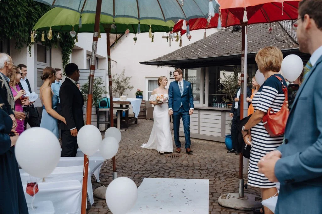 Couple is walking to their wedding ceremony, surrounded by family and friends in Hochheim, Germany.