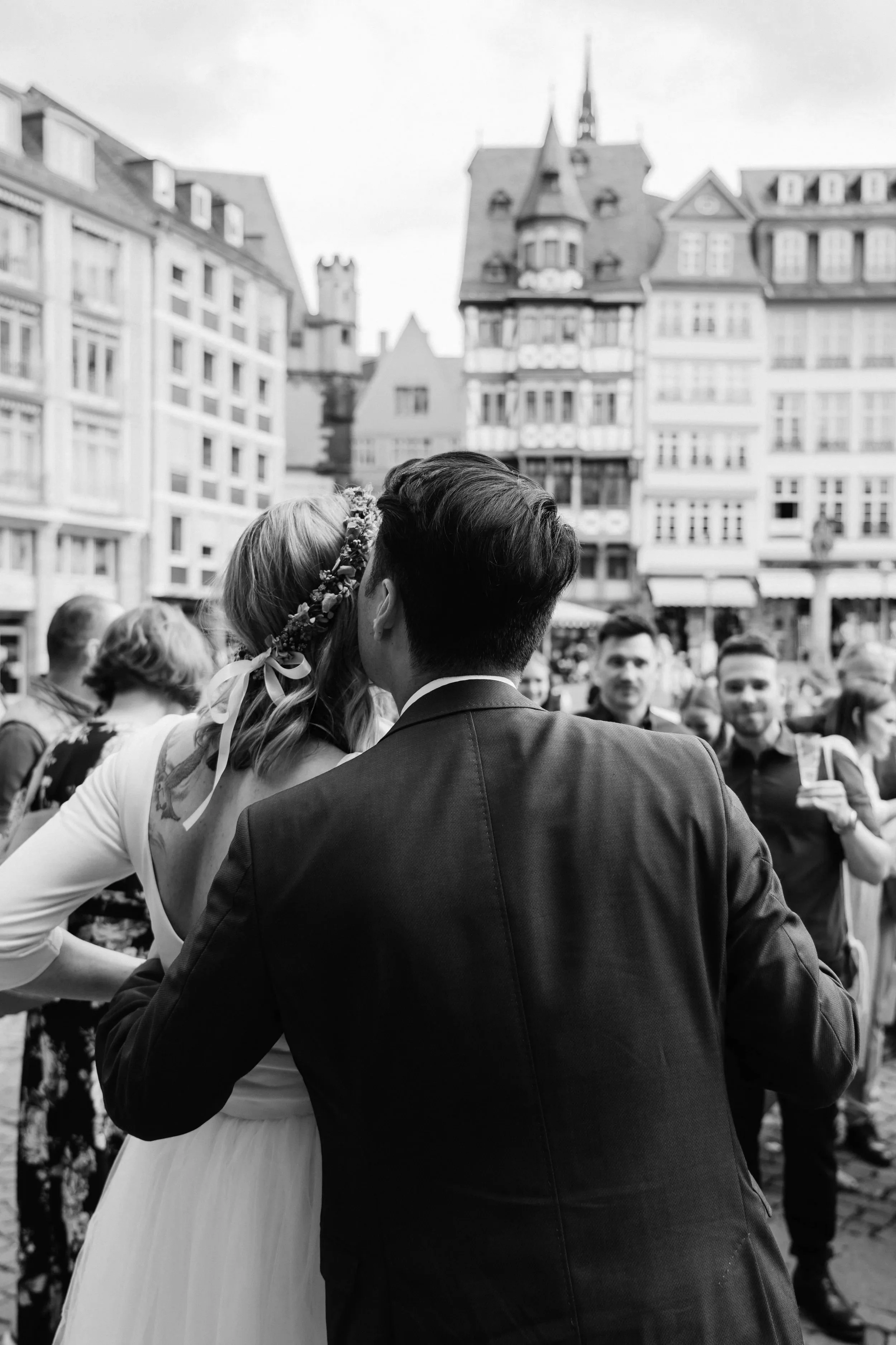 Civil wedding couple kissing in front, friends emotional in background. Frankfurt, Germany.