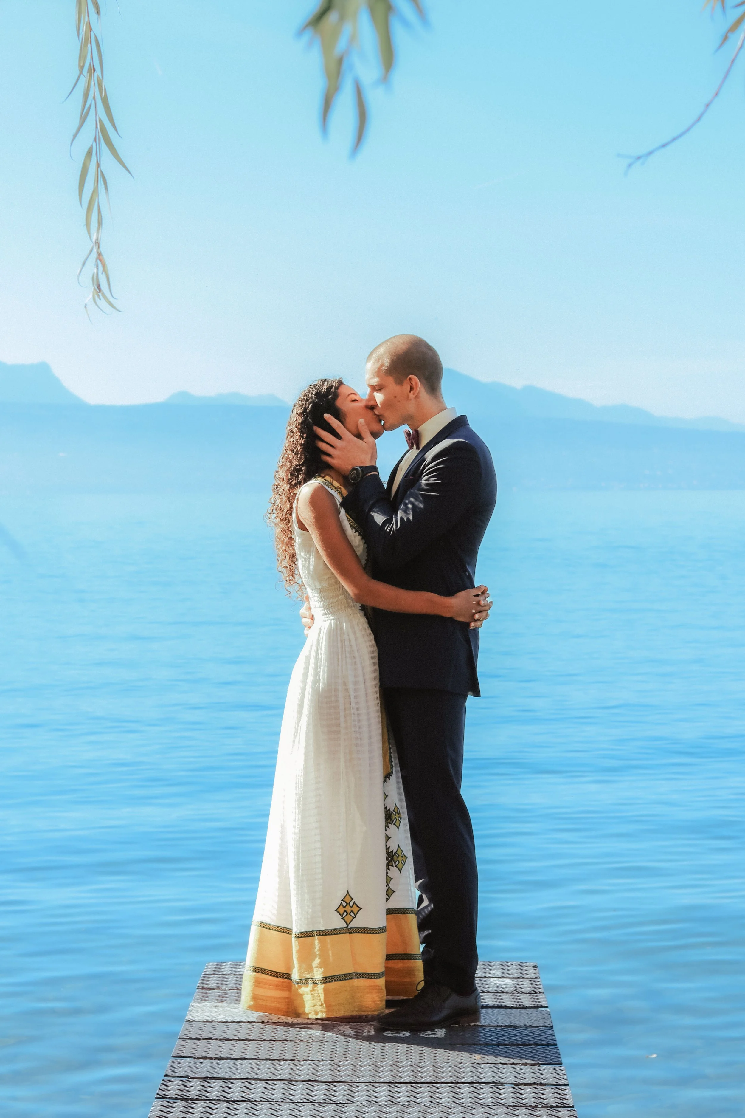 Bride in traditional ethopian wedding dress kissing at Lake Geneva, Switzerland.