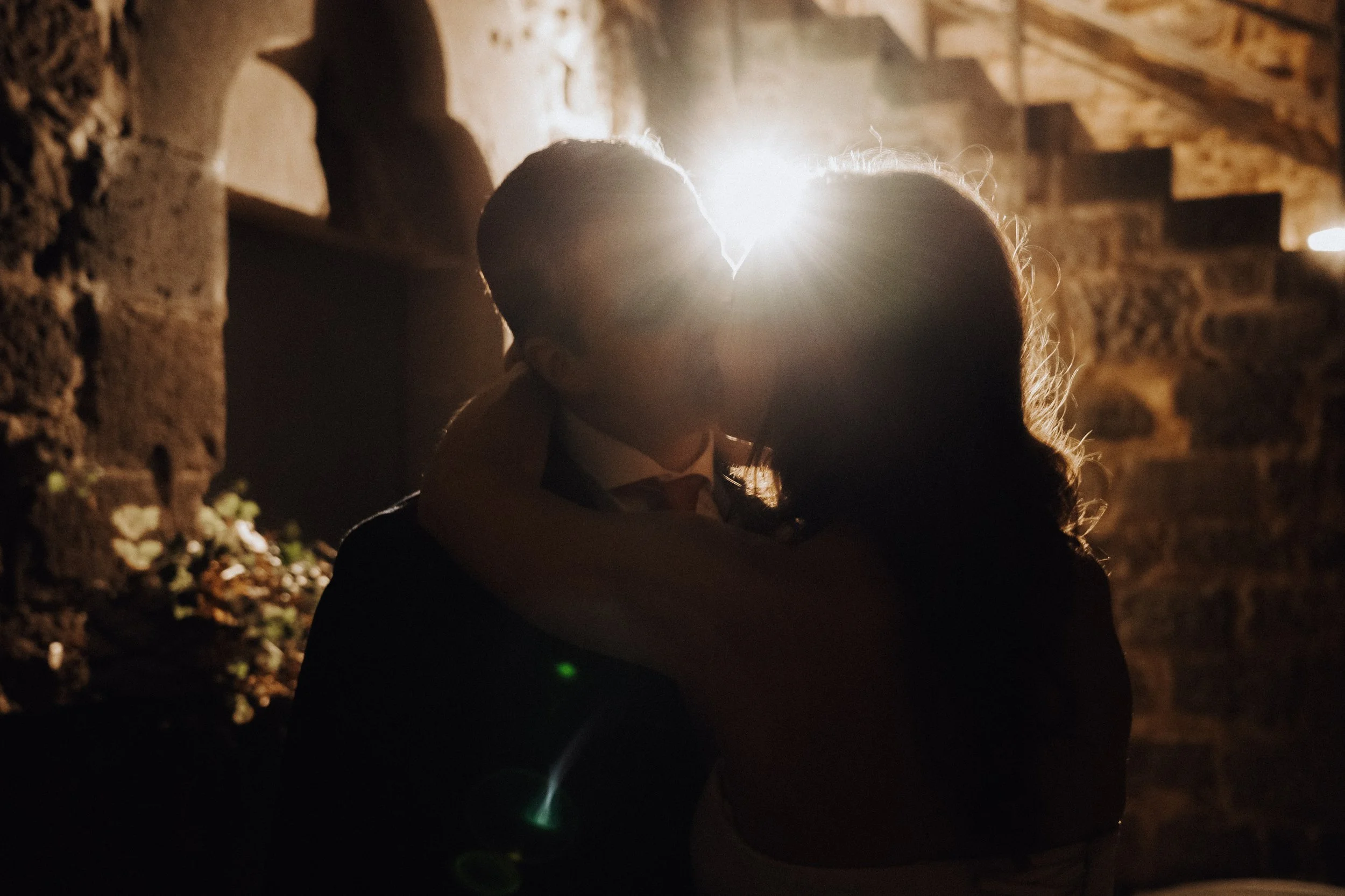 Kiss of bride and groom with dramatic back light captured by cinematic photographer Jessica Di Salvo.