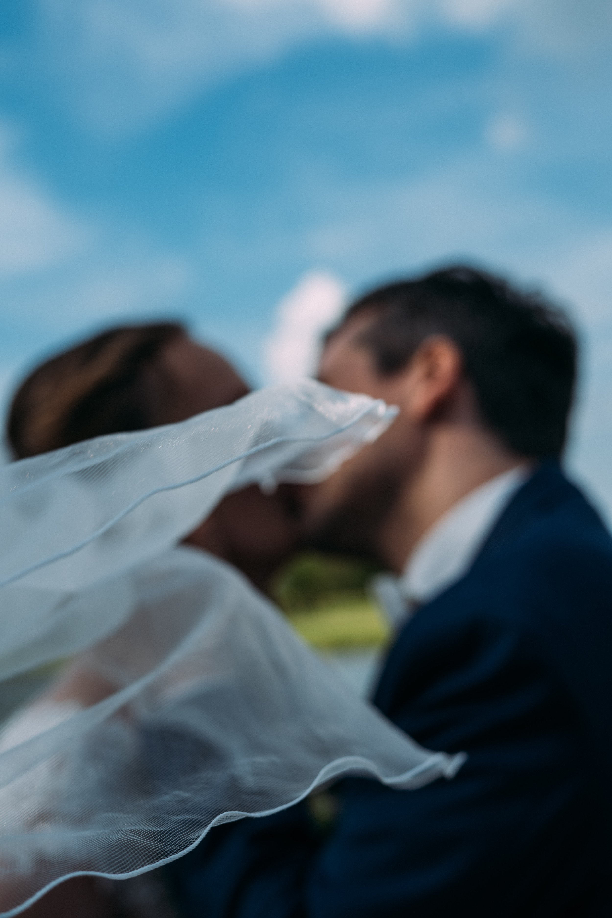 Cinematic kiss of wedding couple with veil in the front, Germany.