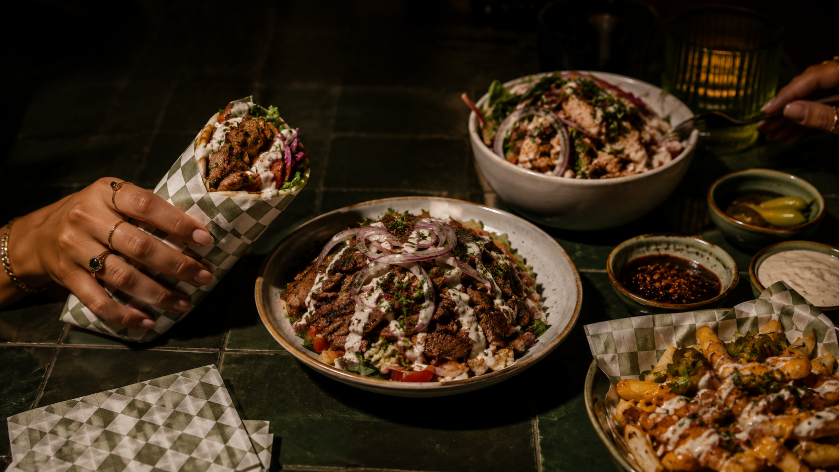 Diversen Mexicaanse gerechten op een tafel, waaronder taco's, salades en sauzen, met handen die het eten vasthouden.