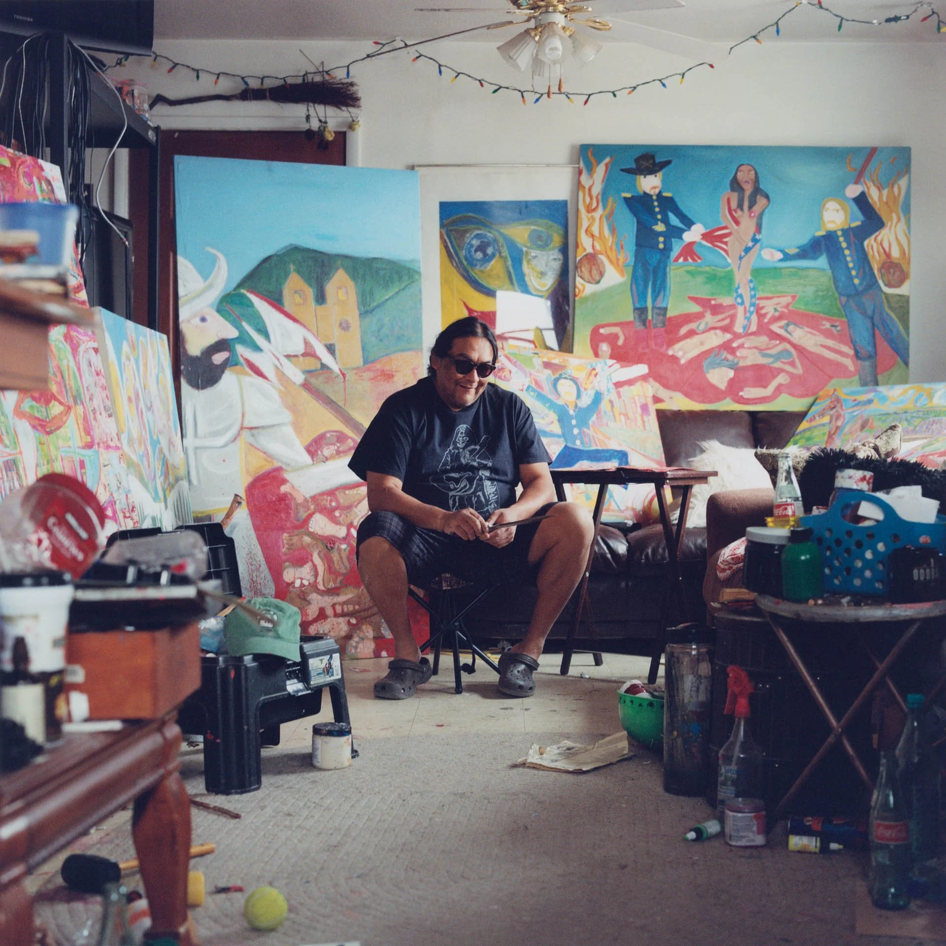 Ishko, an artist of Jicarilla Apache and Diné descent, sits in his art studio on the Isleta Pueblo Indian Reservation in New Mexico surrounded by his artwork that represents some of the atrocities inflicted on Native Americans.