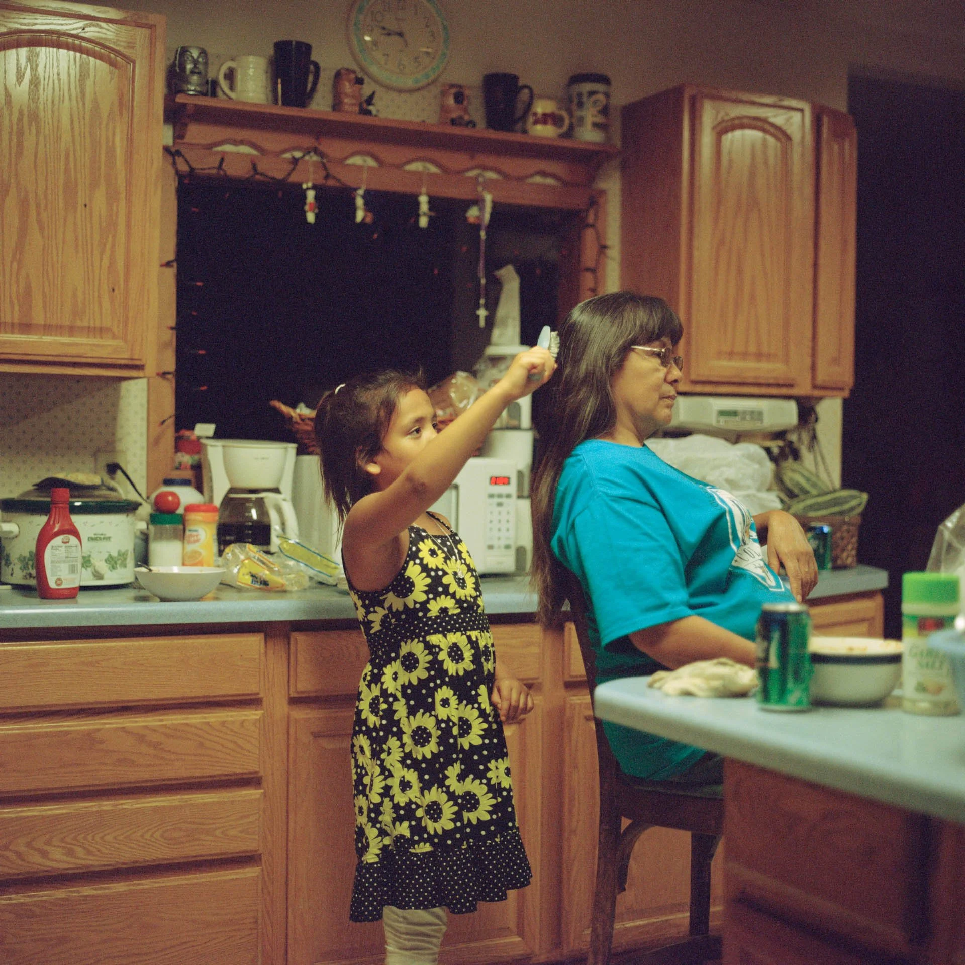 Kennedy, Lakota, brushes her grandma’s hair in the kitchen on the Standing Rock Indian Reservation. She is very close to her grandma and they often bond through cooking and baking together in the kitchen. 