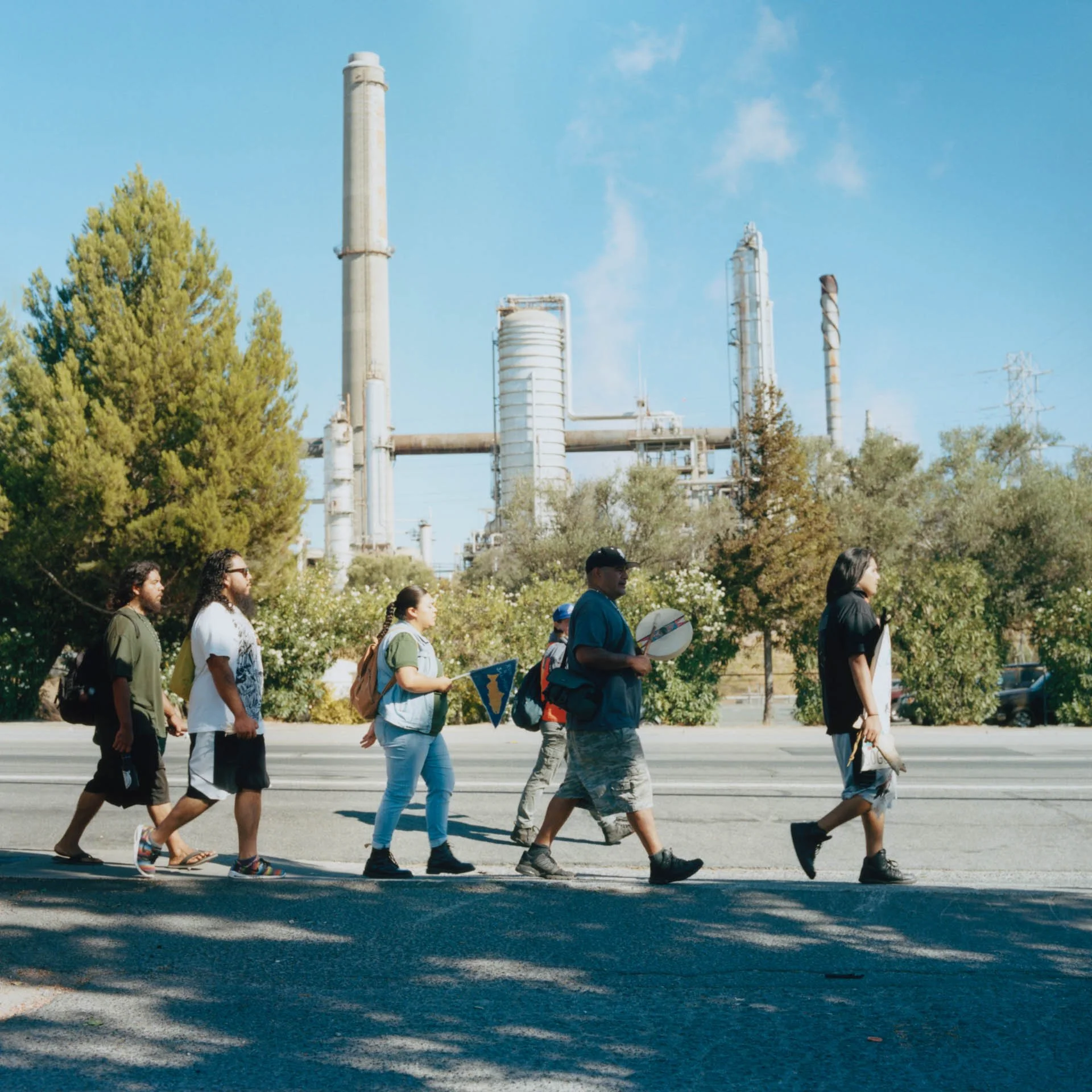 Participants of the Run4Salmon journey walk, sing and drum as they pass by an oil and gas refinery outside of Martinez, CA.