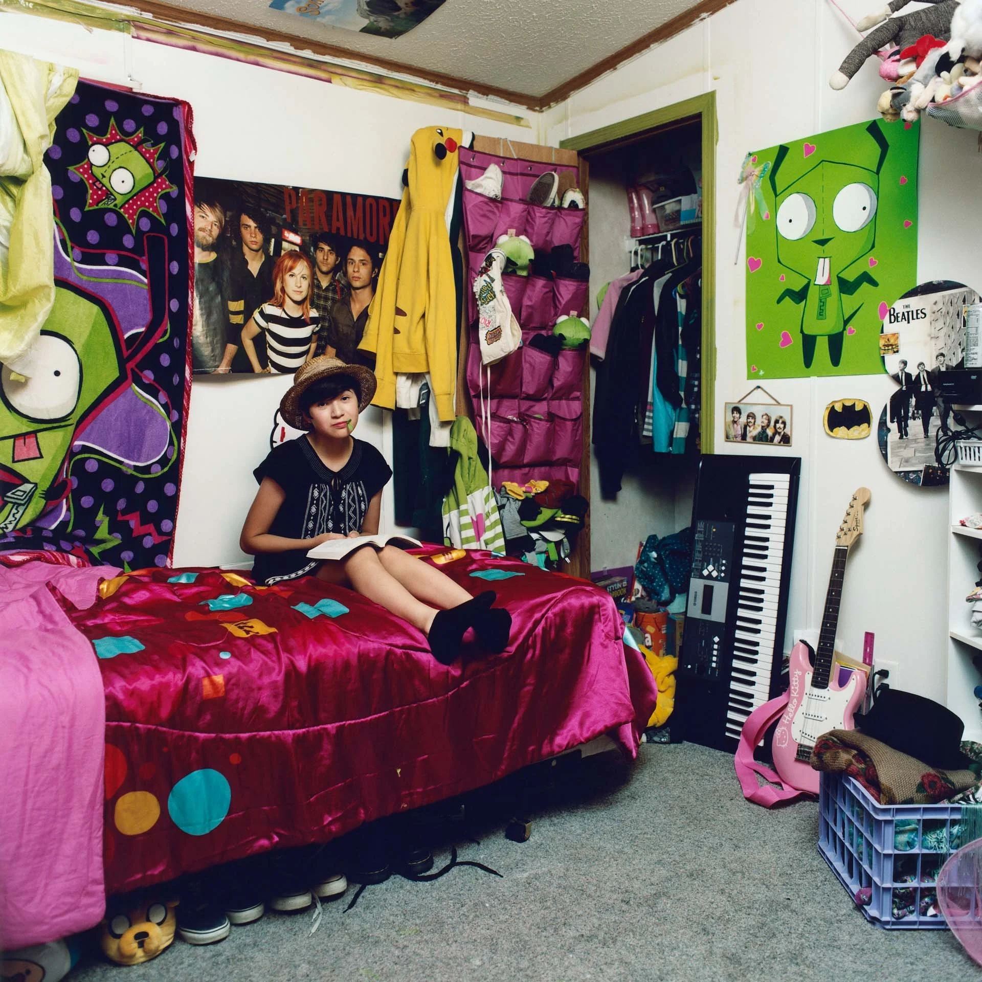 Wahpé, a young Lakota teen sitting in her bedroom on the Pine Ridge Indian Reservation in South Dakota. She formed a band with her father and brother called “Scatter Their Own” and are all self-taught musicians. They tour around Indian Country and pe