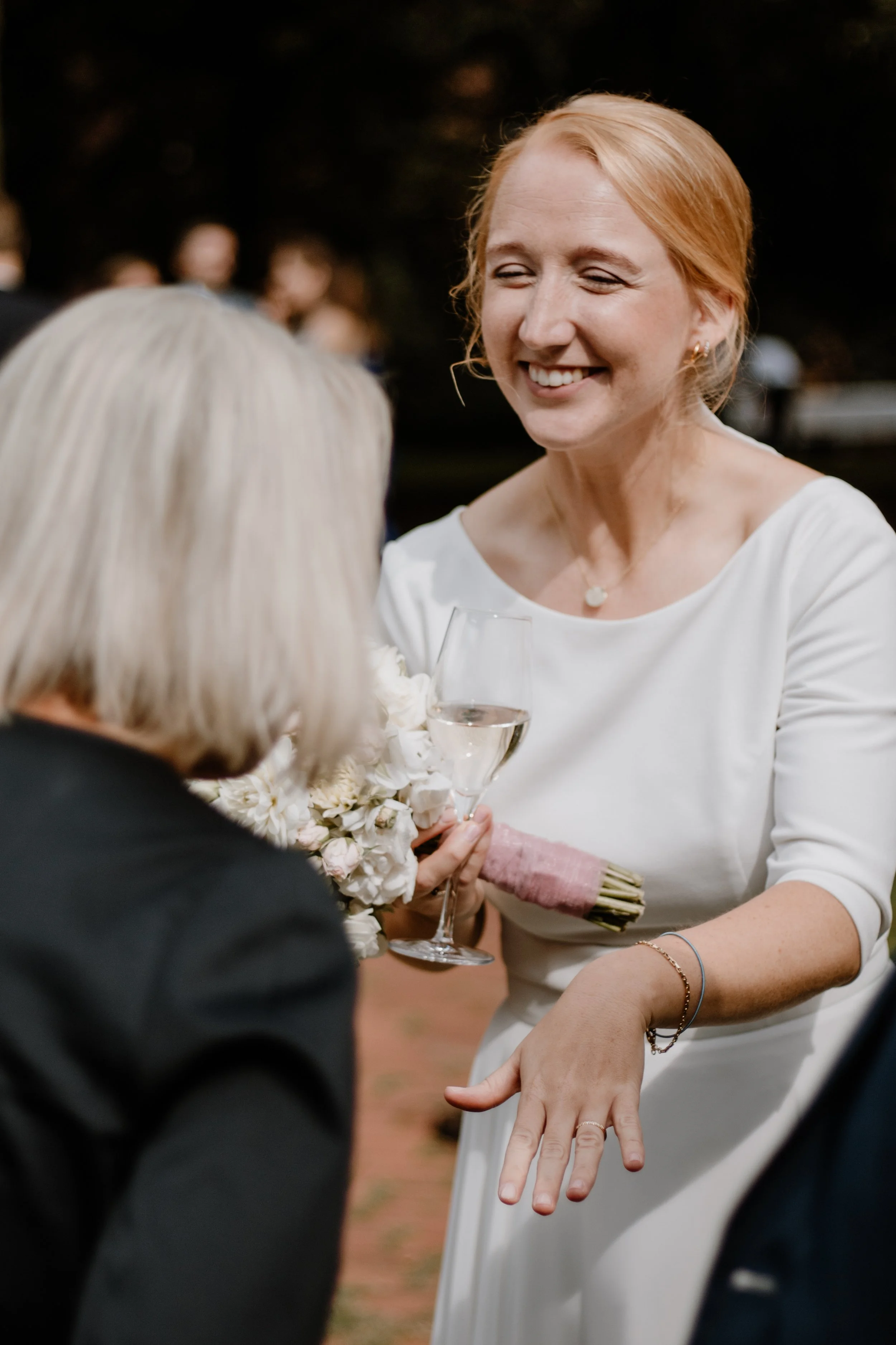 Frau bei einer Feier, die ein Glas Champagner hält und sich an einem Tag mit dunklem Himmel befindet.